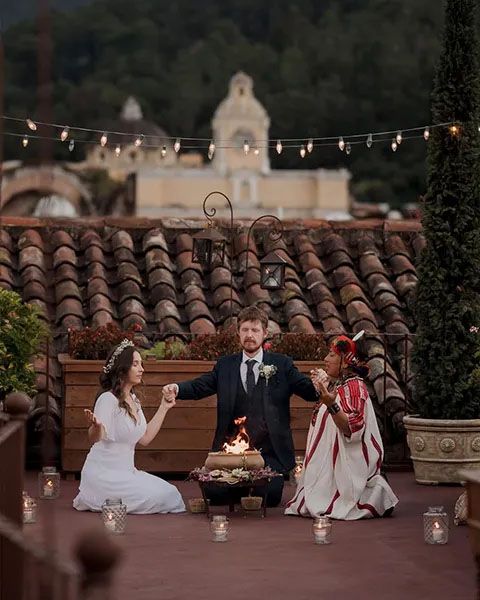 At a rustic venue with Spanish tile roofs and string lights, a celebration unfolds on the outdoor patio at dusk.