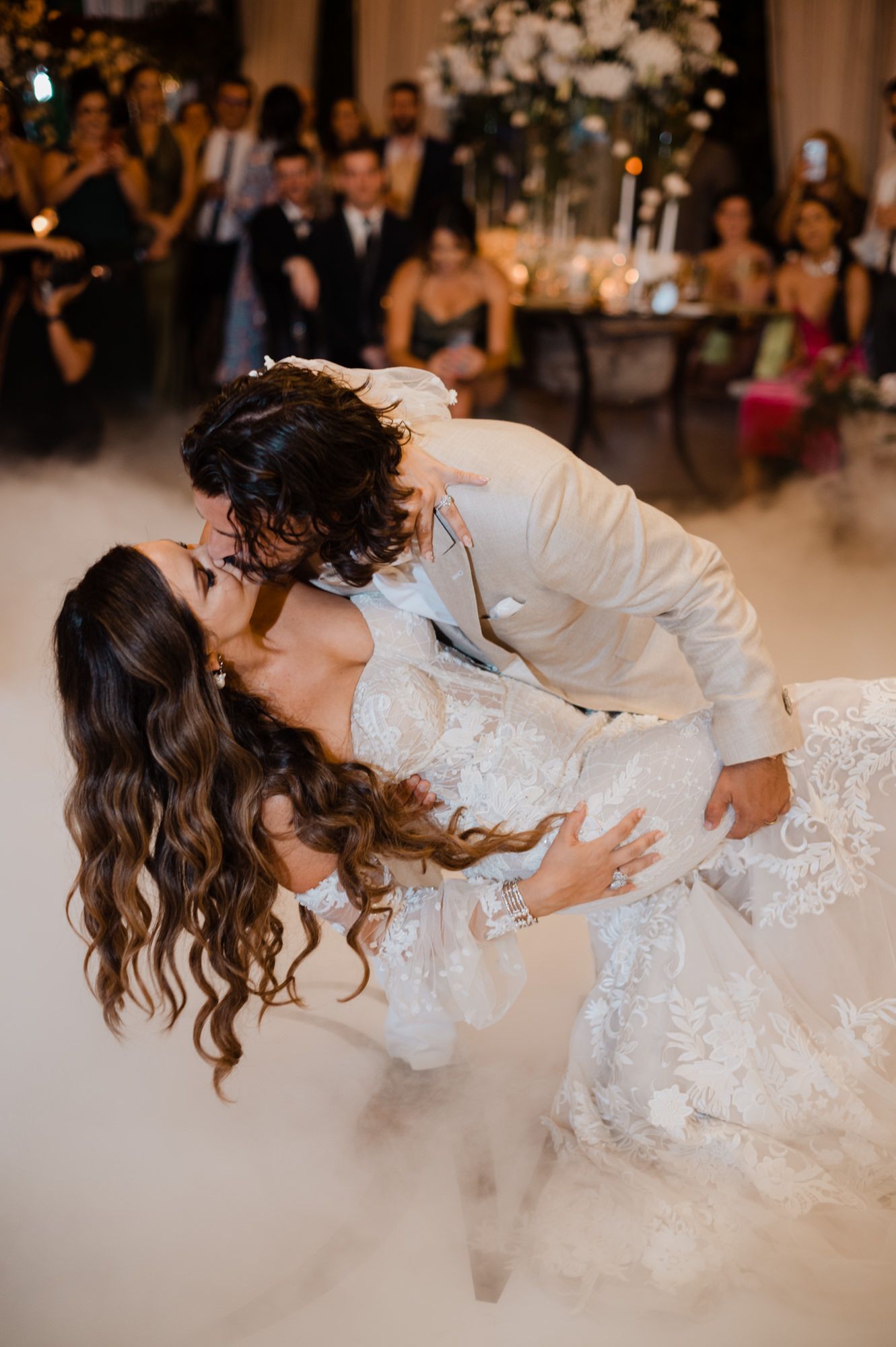 A romantic wedding dance dip captured during an elegant reception with floral decorations.