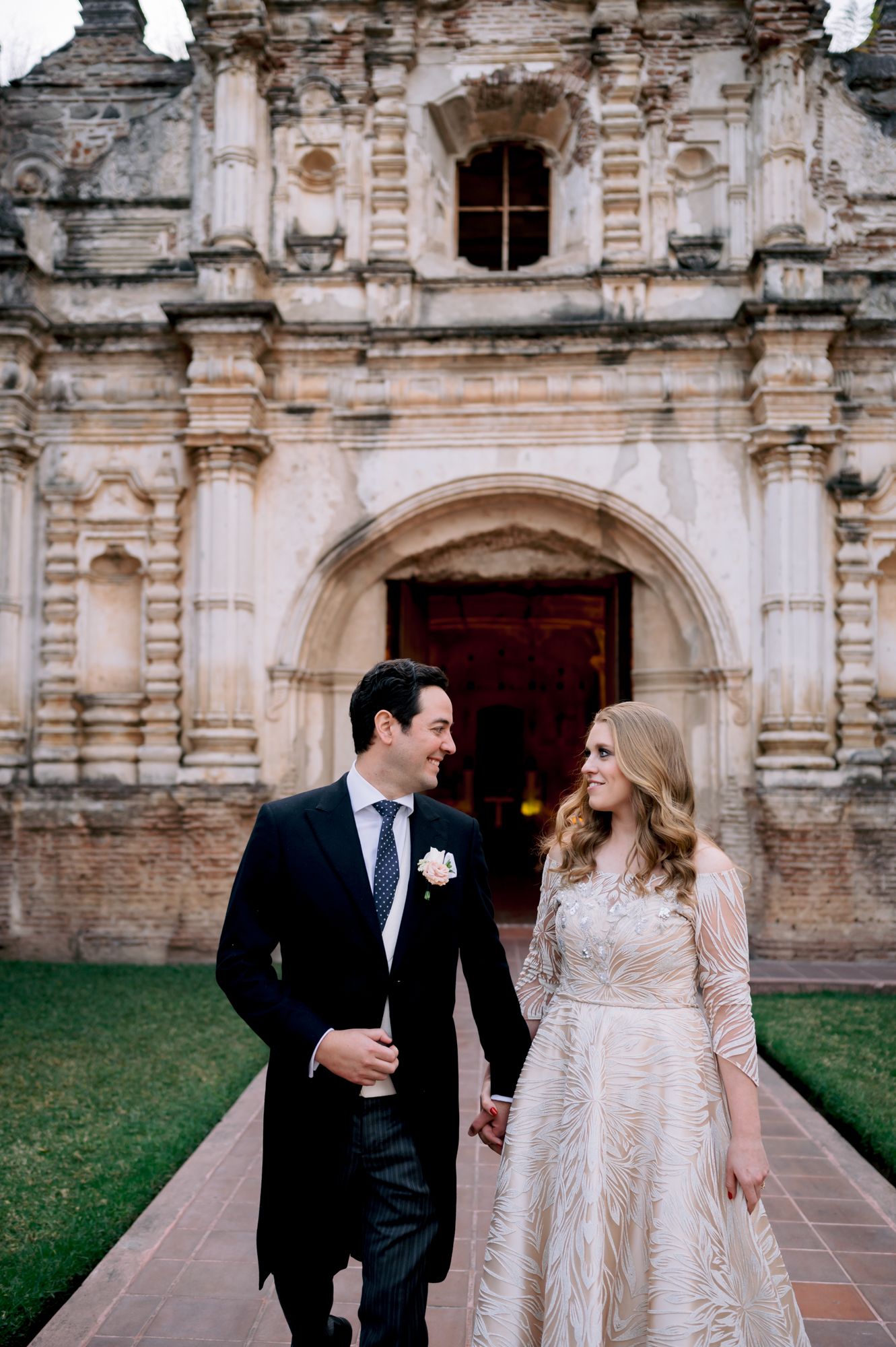 Wedding couple shares intimate moment outside historic stone church facade.