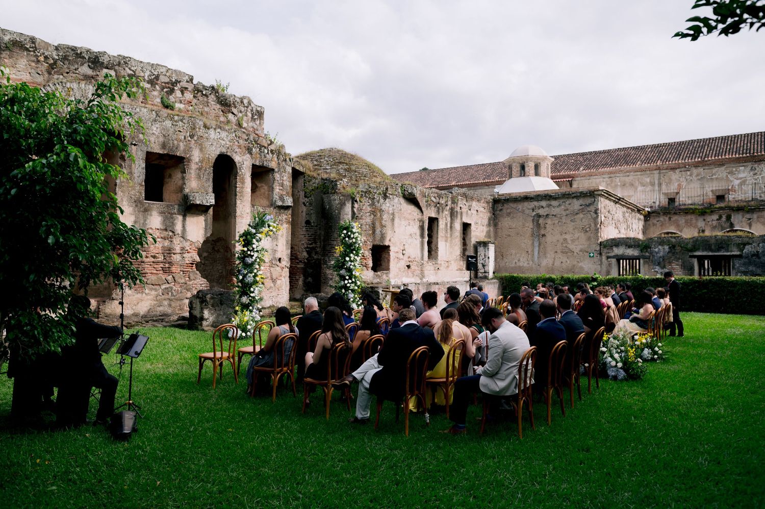 Outdoor wedding ceremony setup with chairs on grass in front of historic stone ruins.