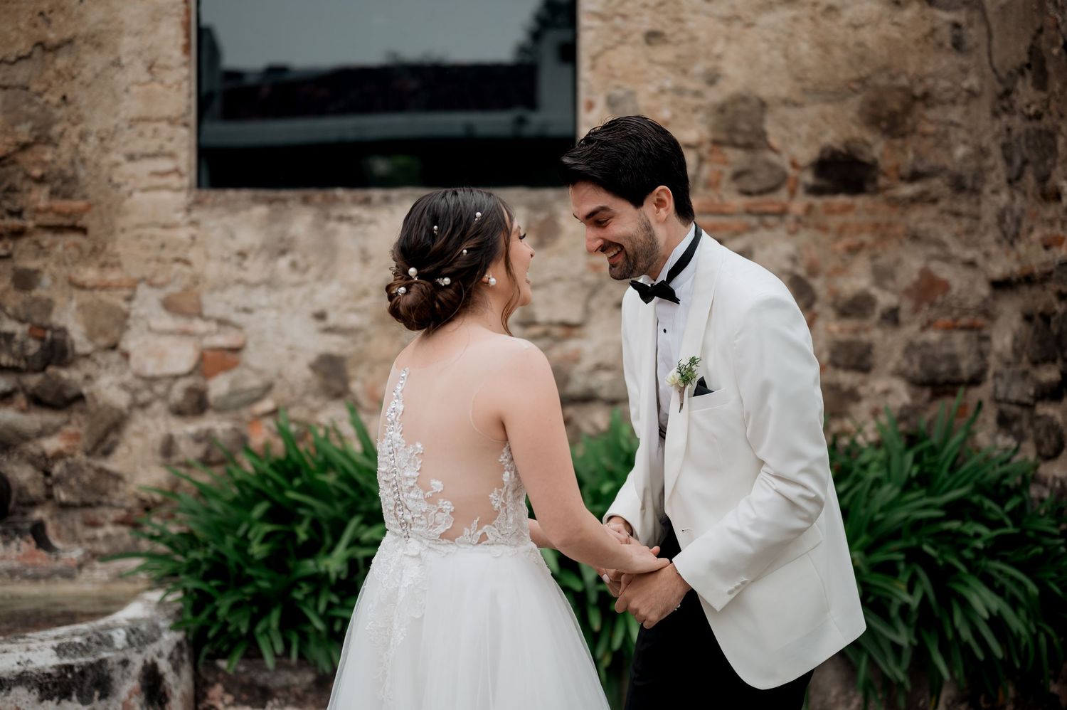 Intimate wedding moment shared against rustic stone architecture.