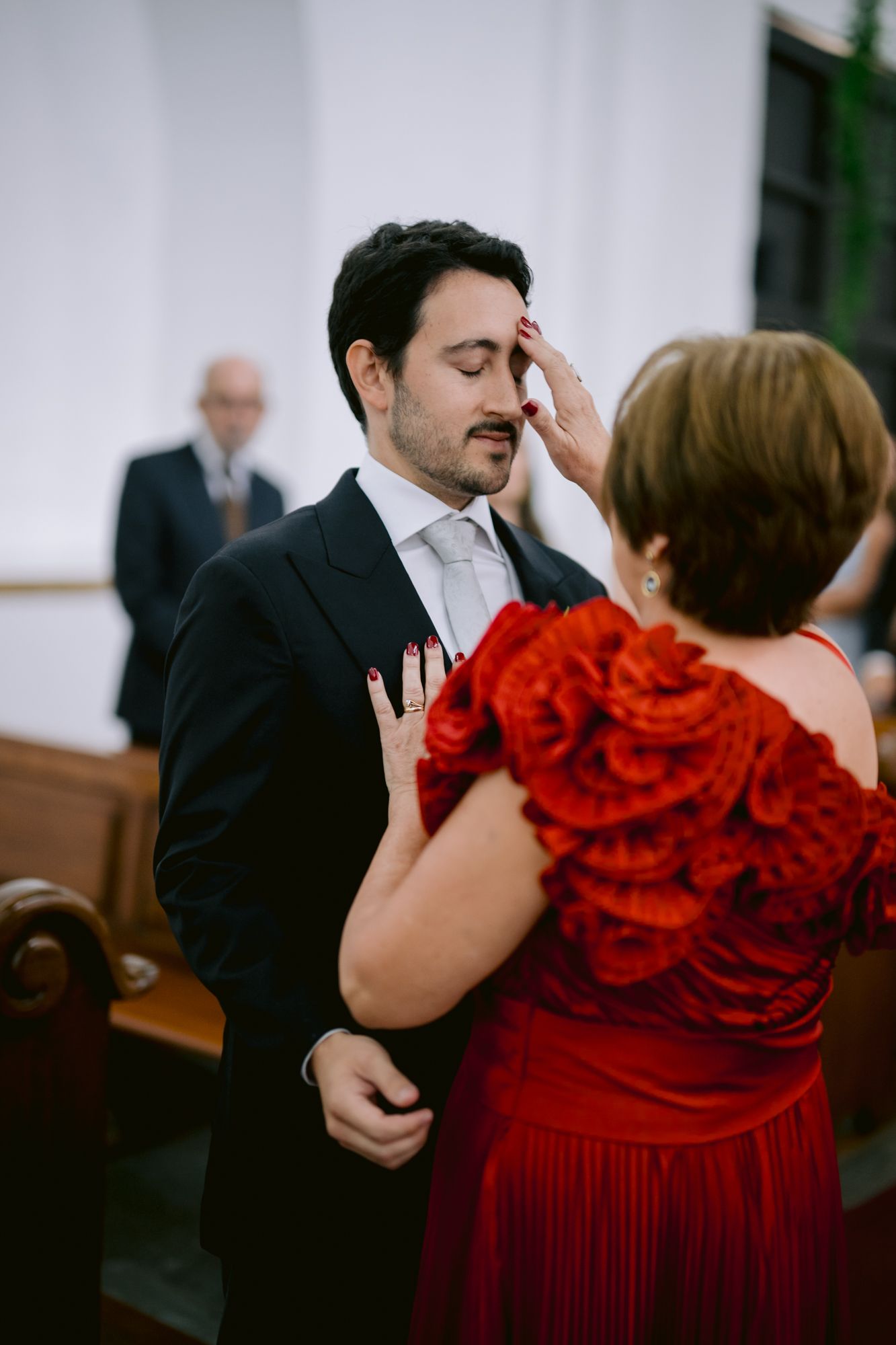 Tender moment during wedding ceremony with woman in red dress comforting someone.