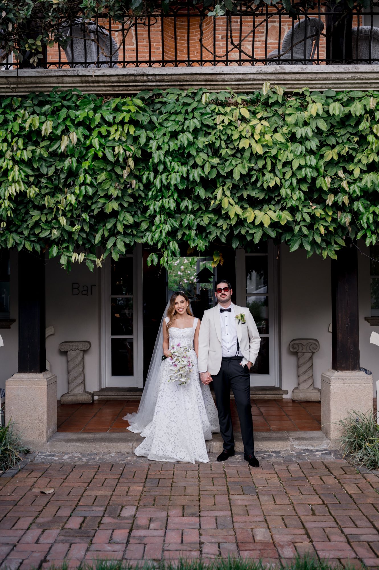 A couple shares a romantic moment under an ivy-covered porch at their wedding.