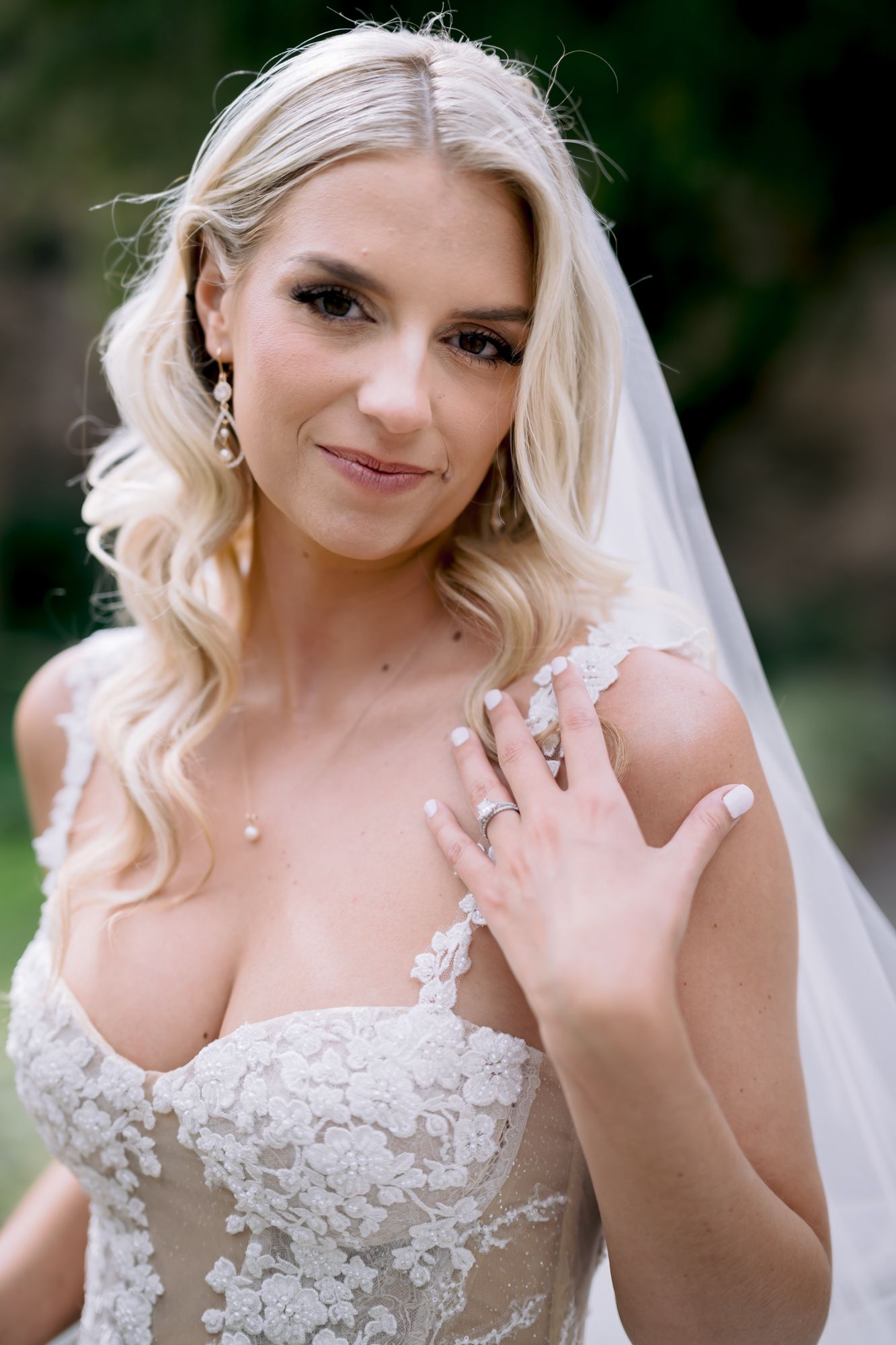 Close-up portrait of bride wearing lace gown and veil with elegant jewelry.