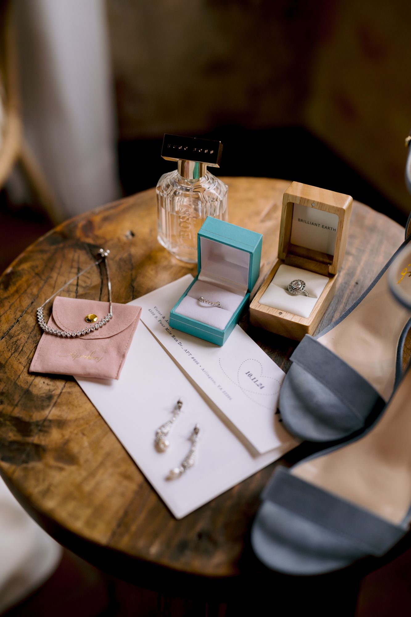 Wedding accessories including jewelry box, perfume, and earrings arranged on wooden table.