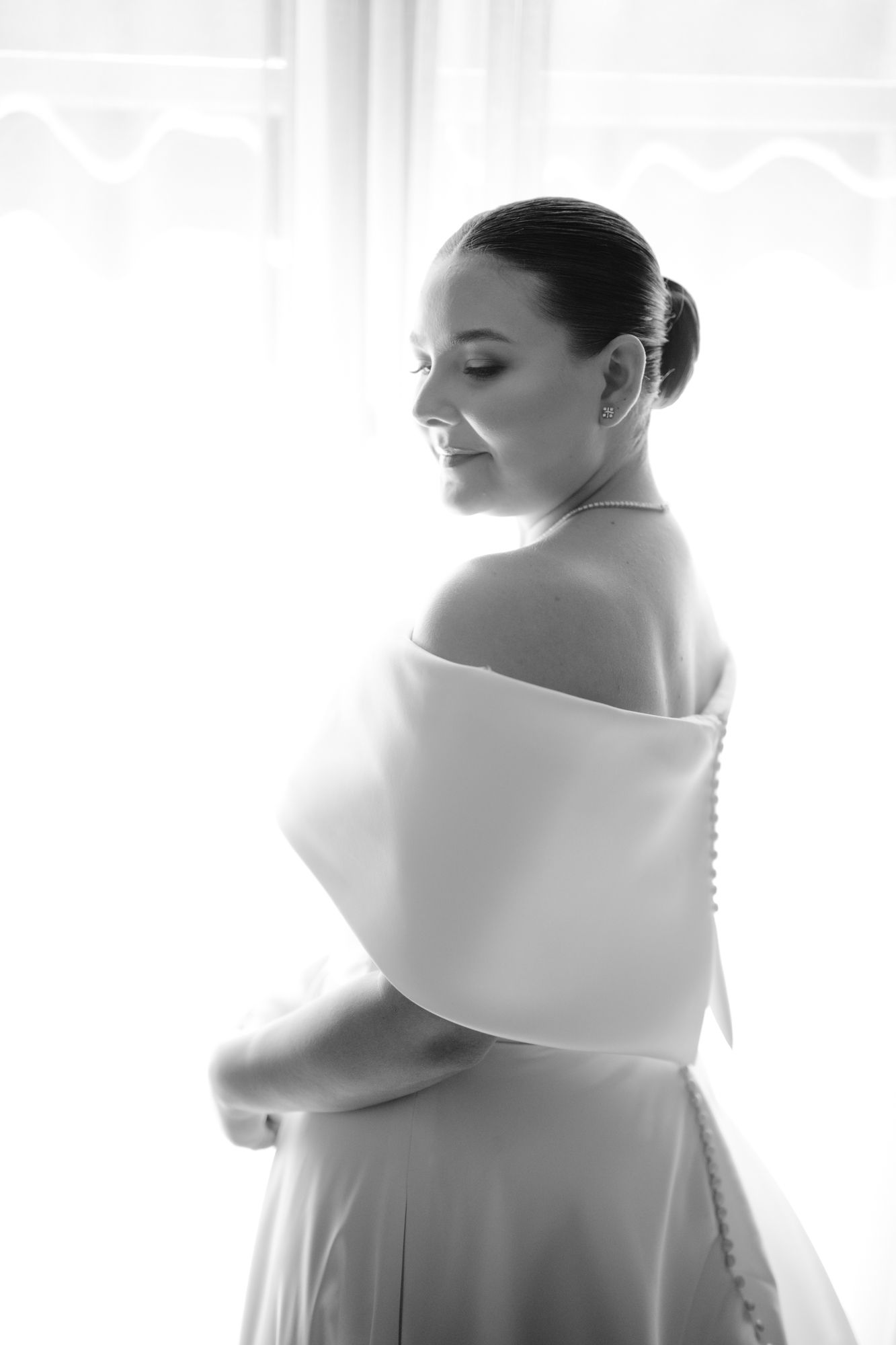 Black and white portrait showing elegant off-shoulder wedding dress from behind.