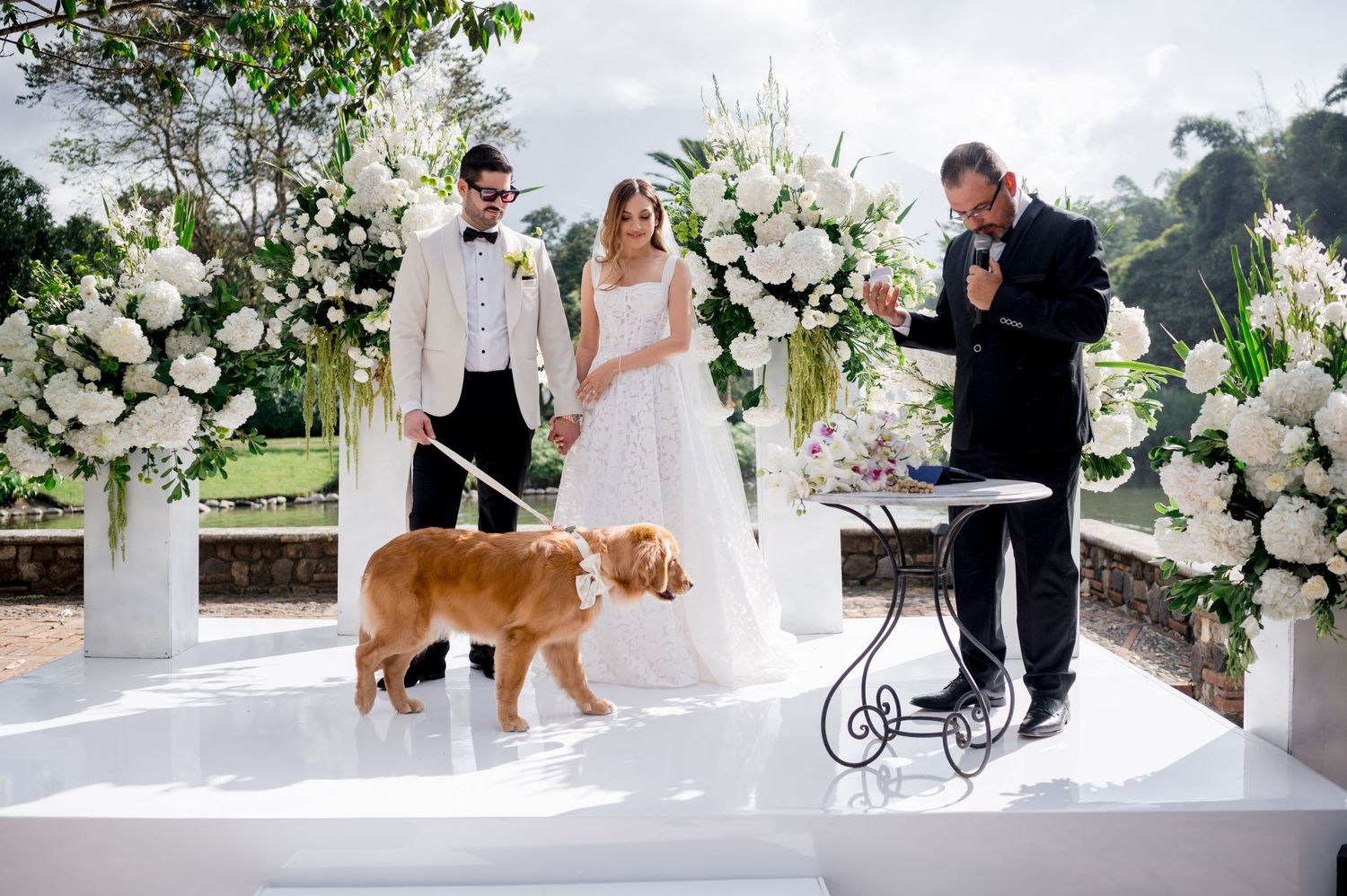Wedding ceremony setup with white floral arrangements and a golden retriever participating.