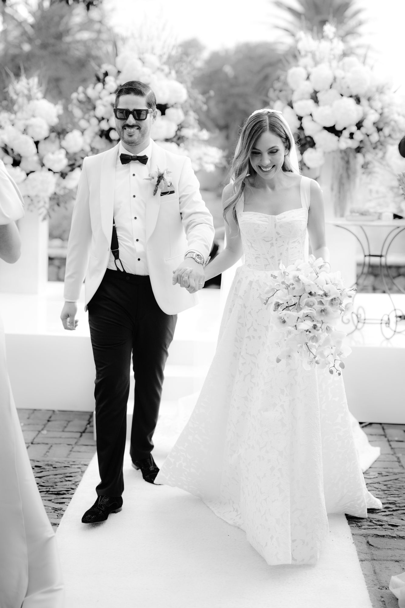 Black and white wedding photos showing elegant outdoor celebration with white floral decor.