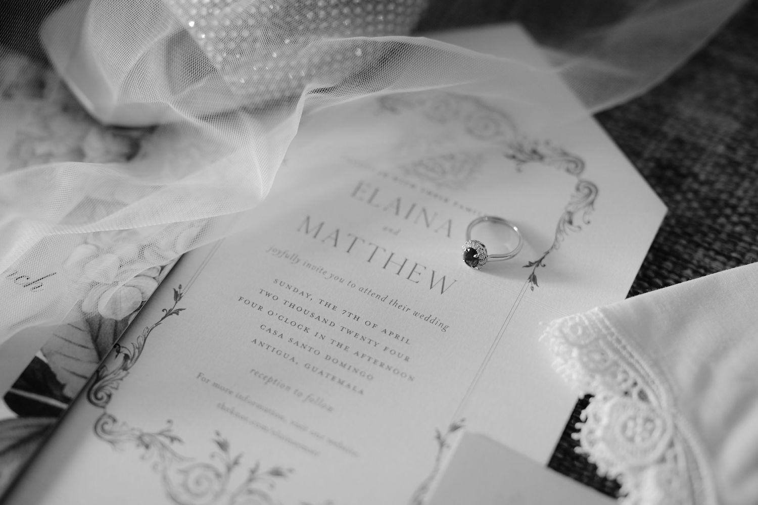 Black and white close-up of an elegant wedding invitation with decorative details.