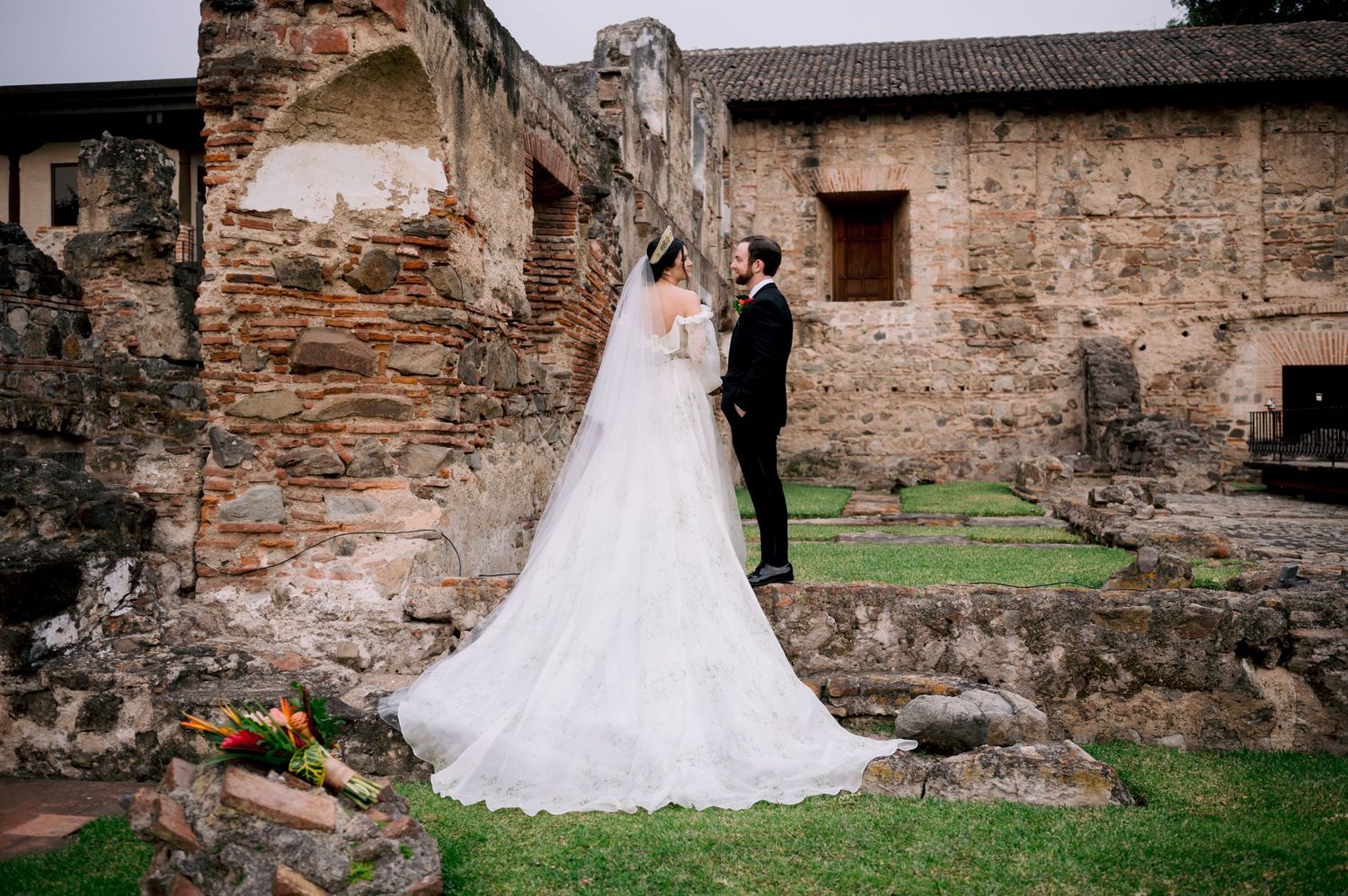 Wedding couple photographed in front of weathered stone ruins with long train dress.