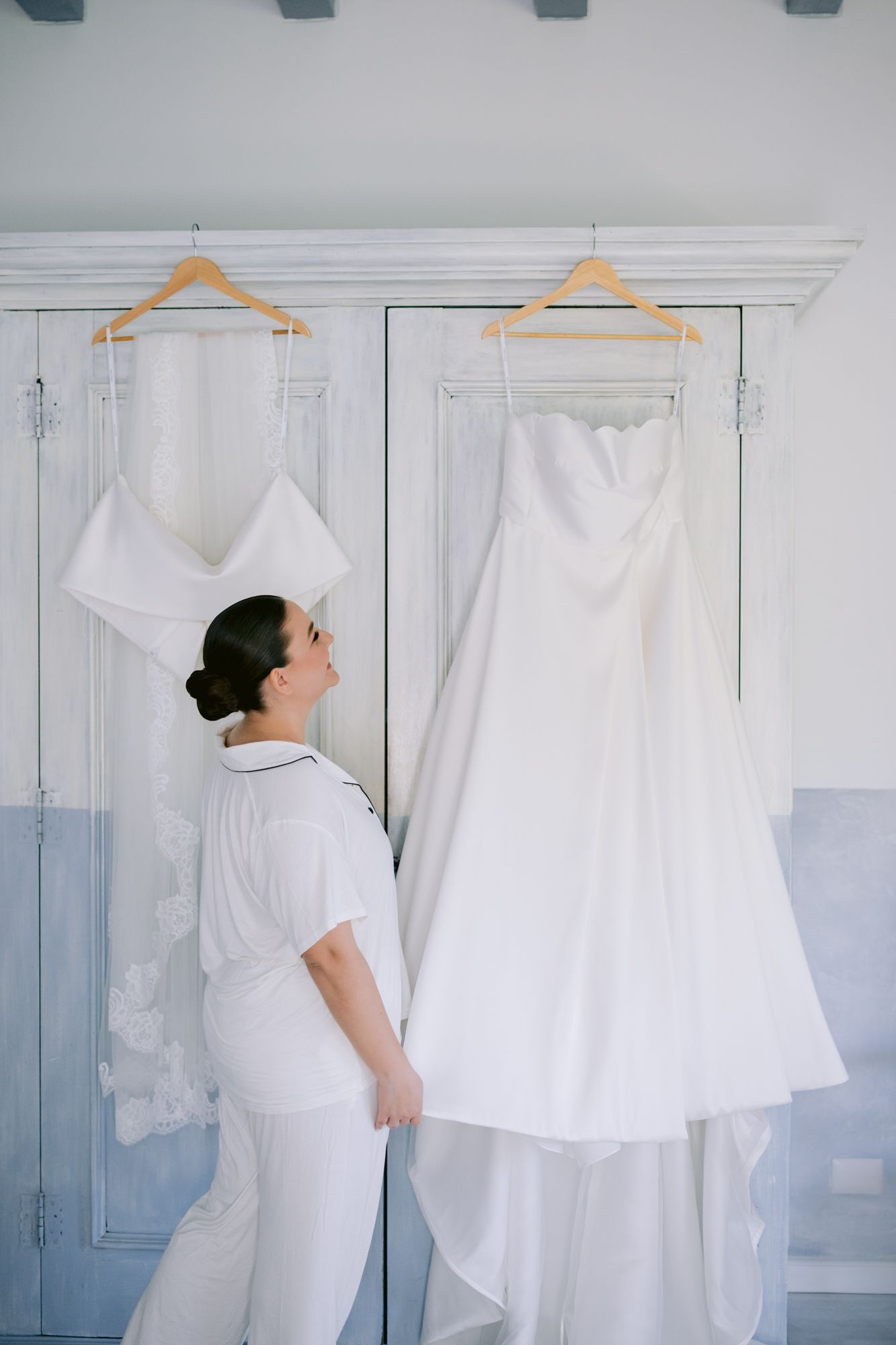 Wedding preparations showing hanging white gown and dress shop interior with blue and white walls.
