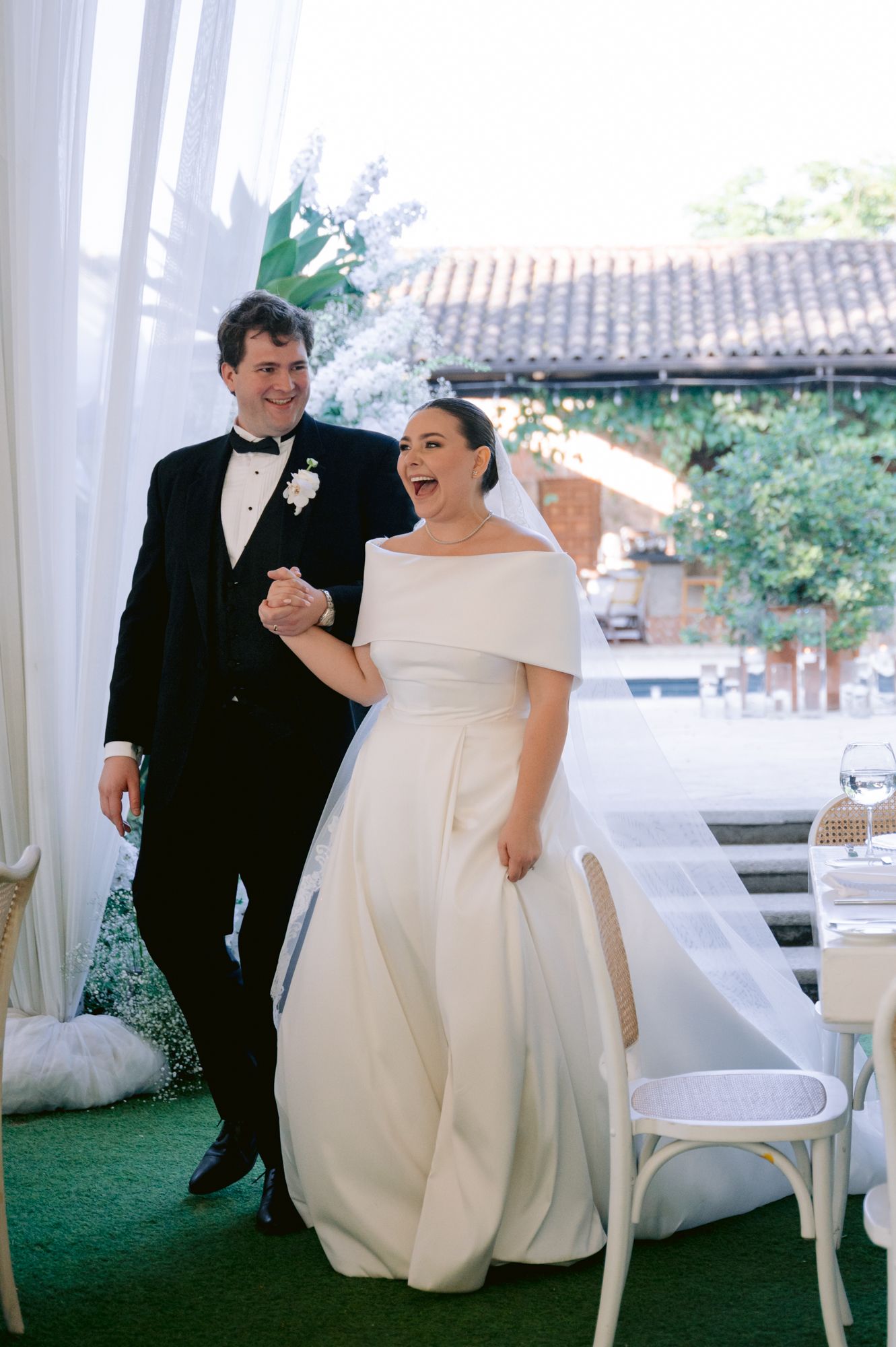 Candid moment of newlyweds laughing together under a wedding tent.