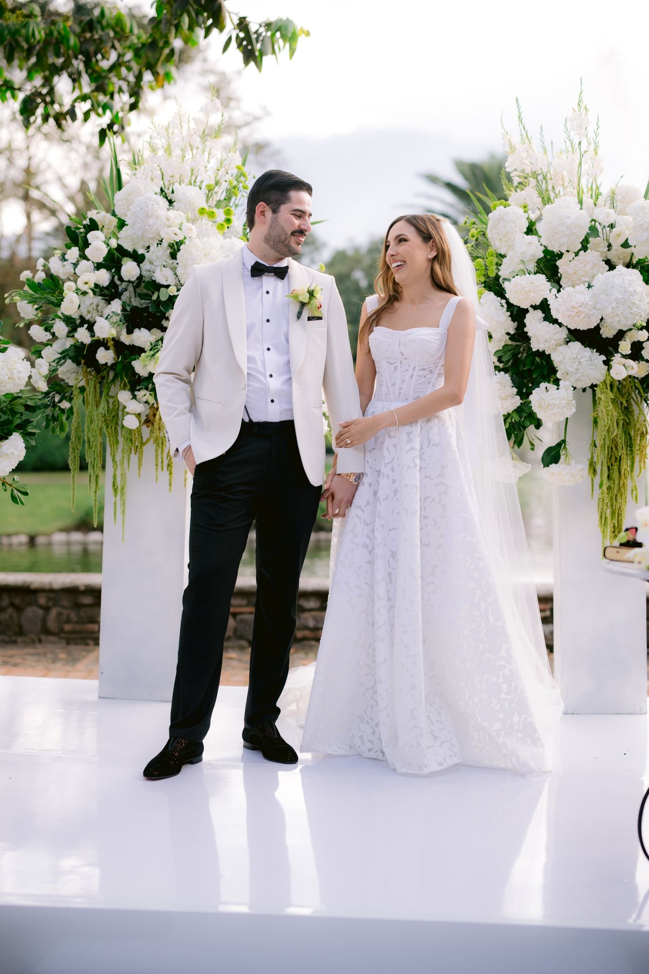 White floral arrangements and decor create an elegant outdoor wedding setting with stone columns.