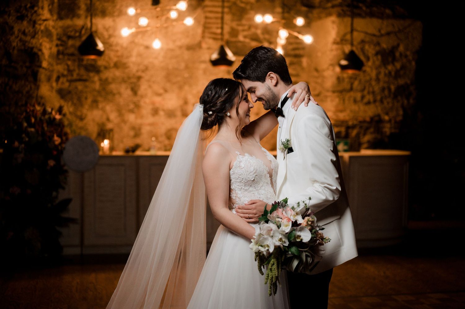 Intimate wedding portrait in romantic venue with warm lighting and exposed brick walls.