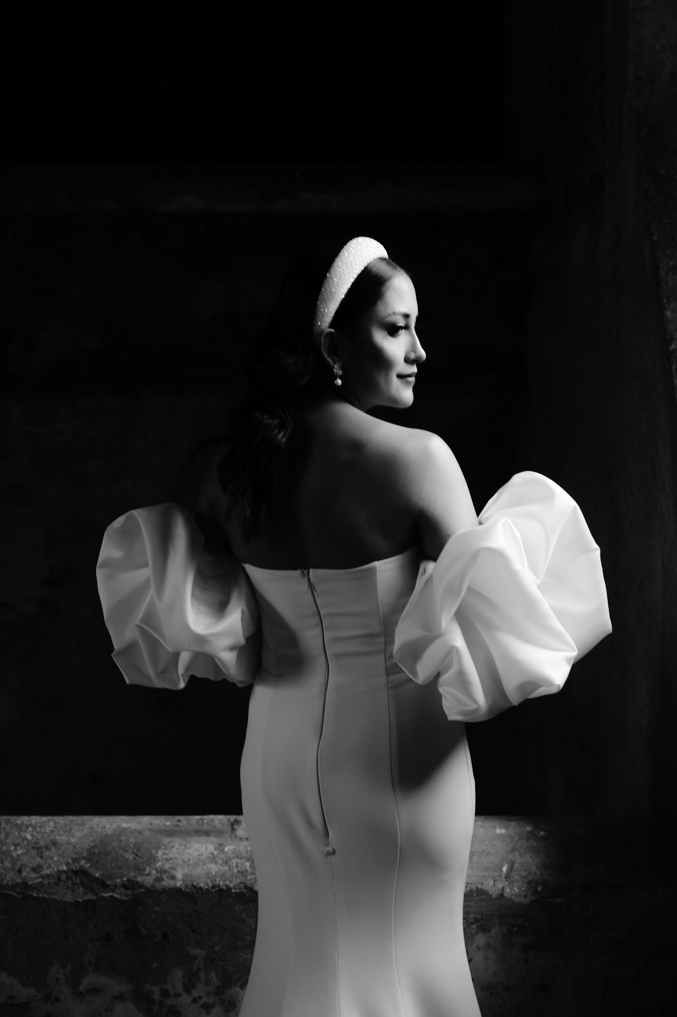A back view of a fitted wedding dress with dramatic puff sleeves in black and white.
