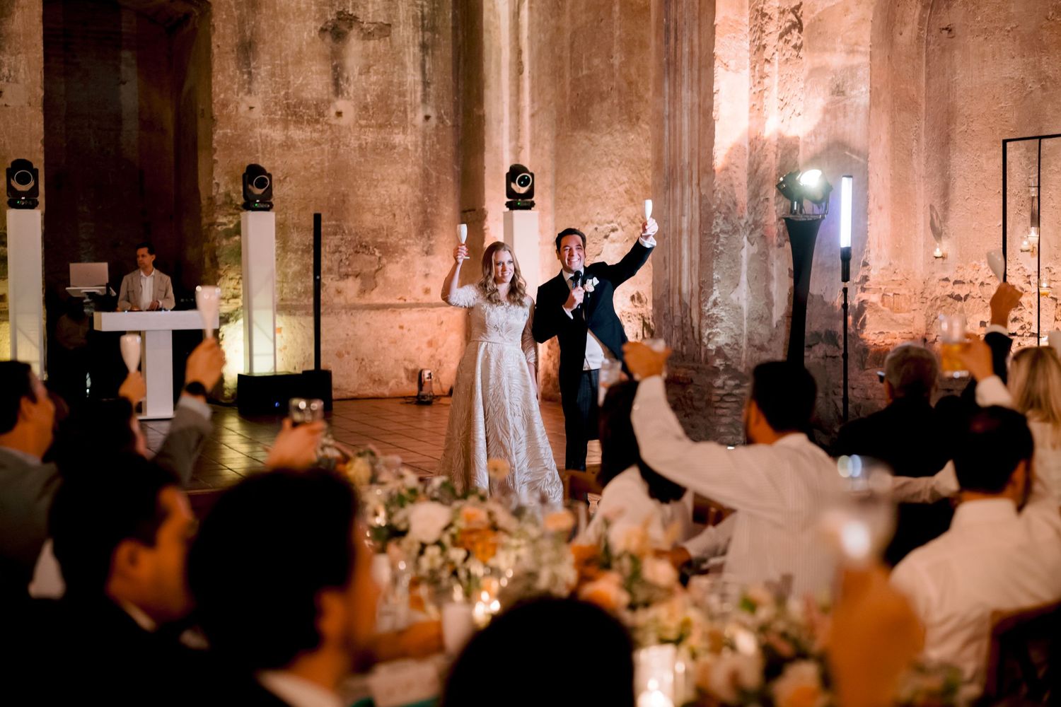 A newlywed couple's first dance surrounded by guests at an elegant reception venue.