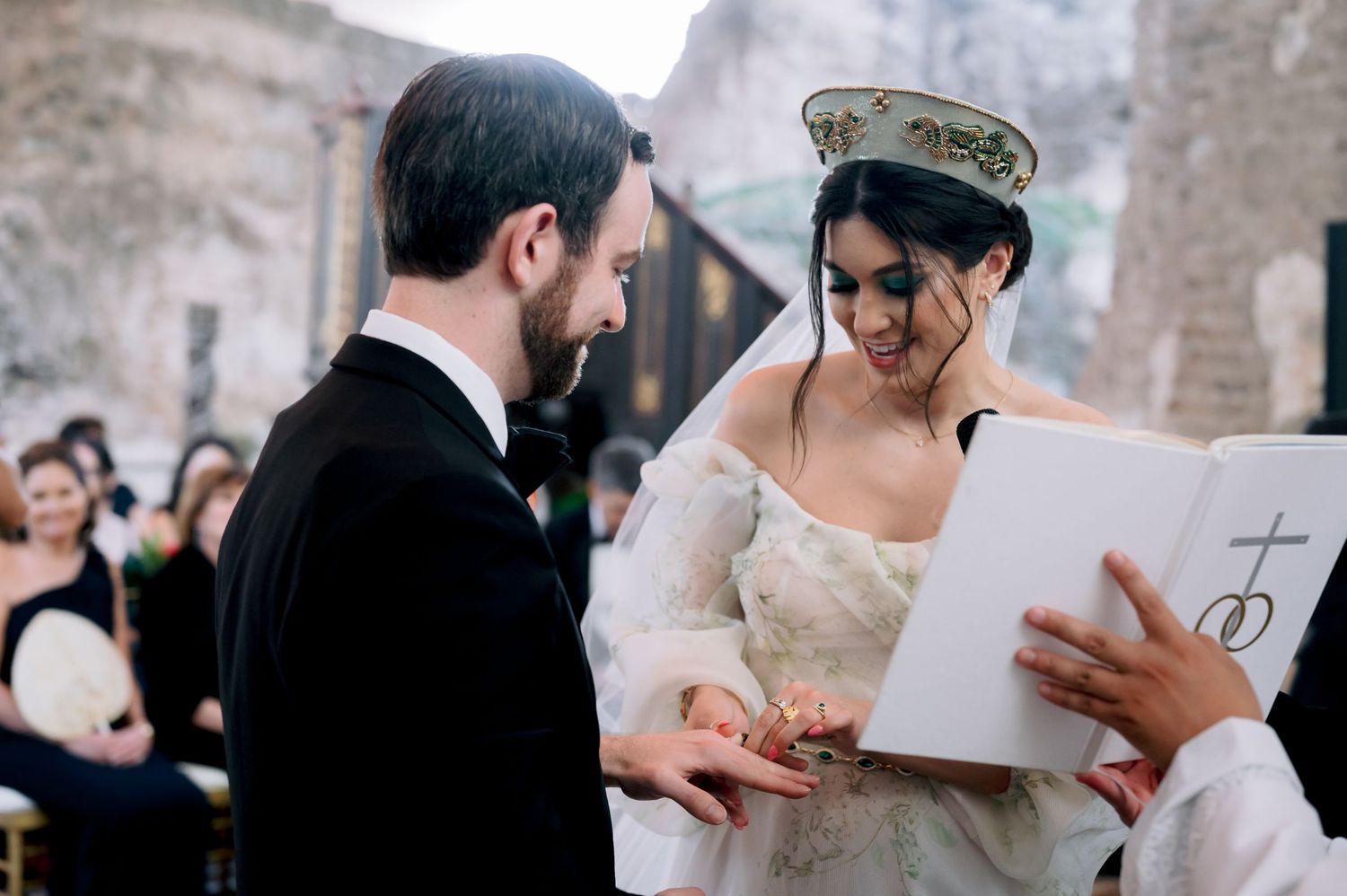 Wedding couple exchanging vows and reading from a ceremonial document in a historic church setting.