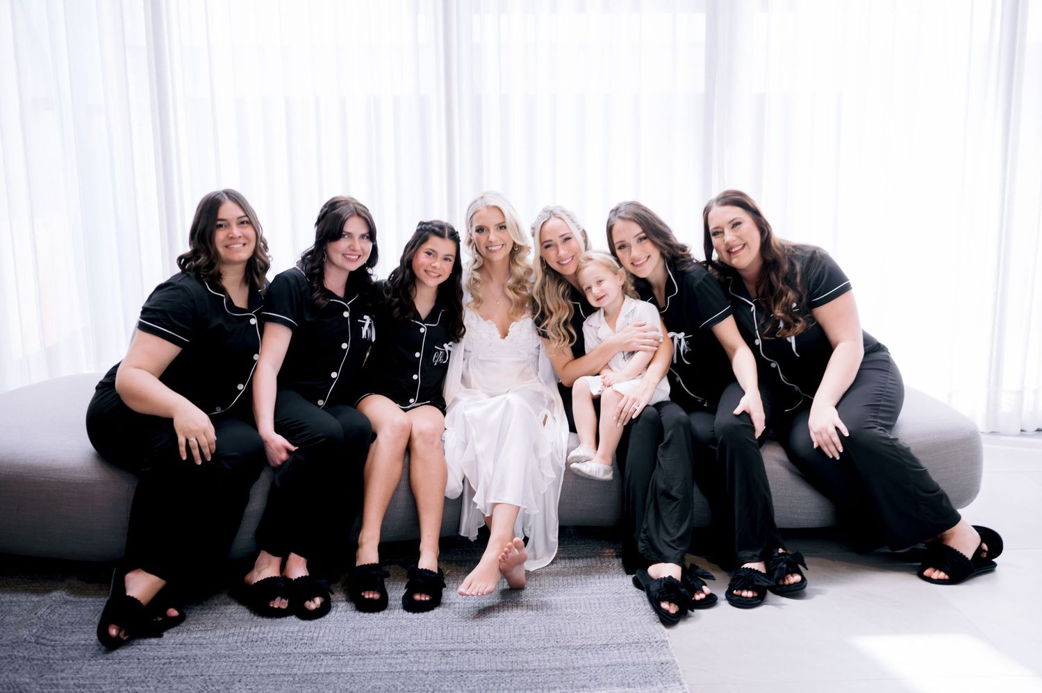 Wedding party in matching black outfits posing together on a couch.