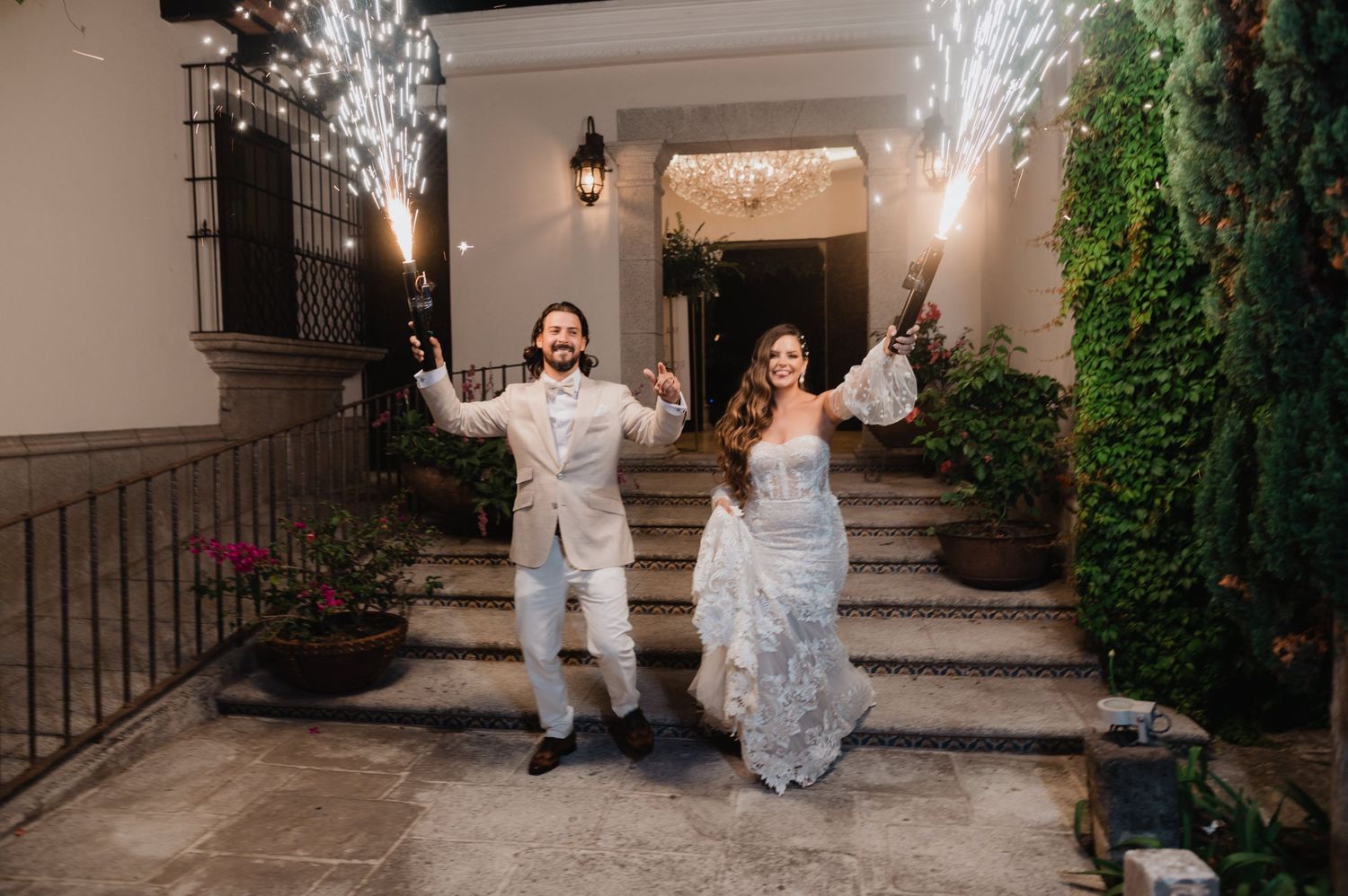 Wedding celebration with sparklers illuminating an elegant courtyard during evening festivities.