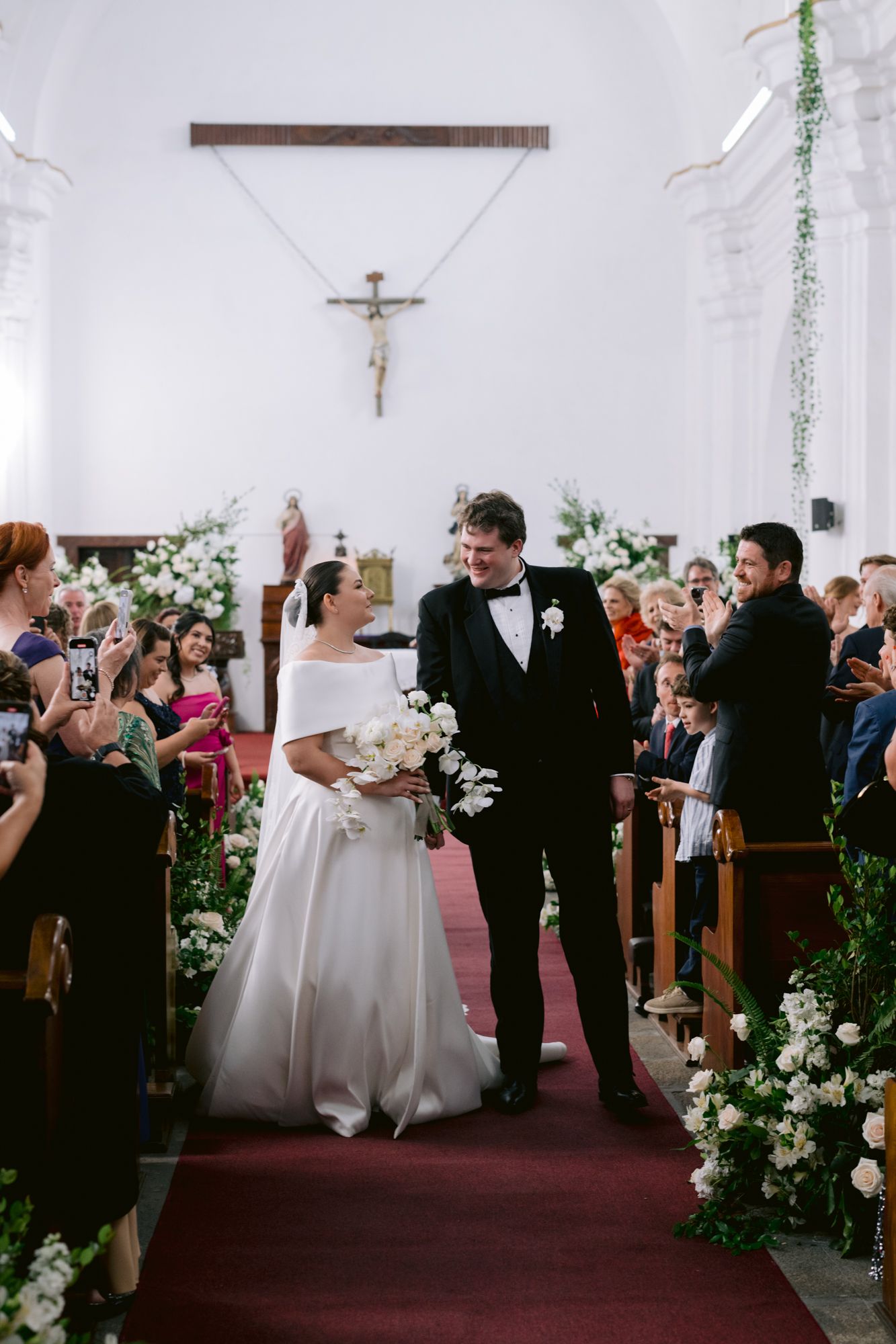 A celebratory moment as the newlyweds exit down the aisle in a beautifully decorated church.