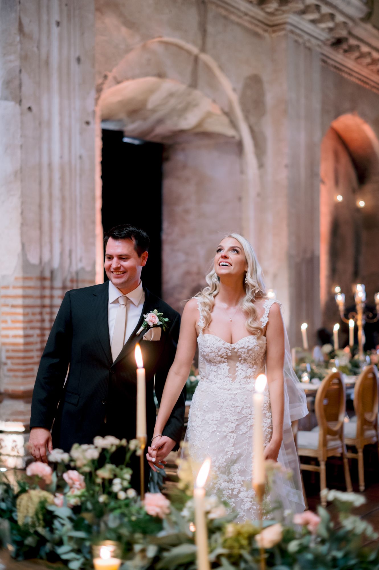 Candlelit wedding celebration in historic stone venue with elegant floral arrangements.