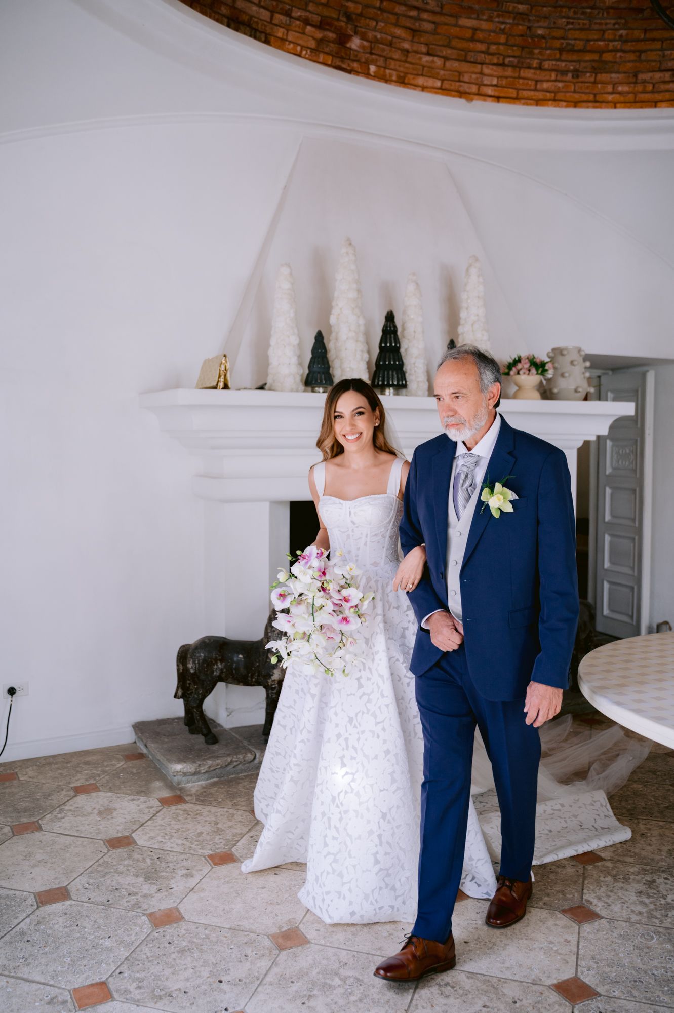 A couple shares a sweet moment during their wedding photoshoot in a white brick-walled venue with elegant decor.