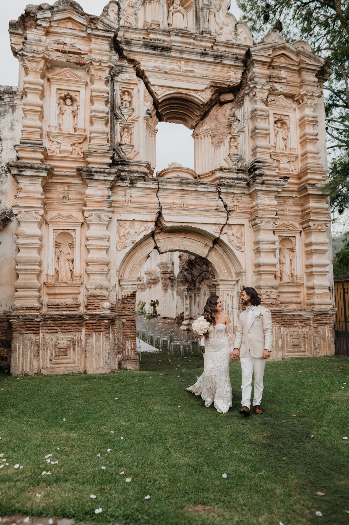 A romantic wedding photo at historic stone ruins featuring elegant white attire and architectural details.