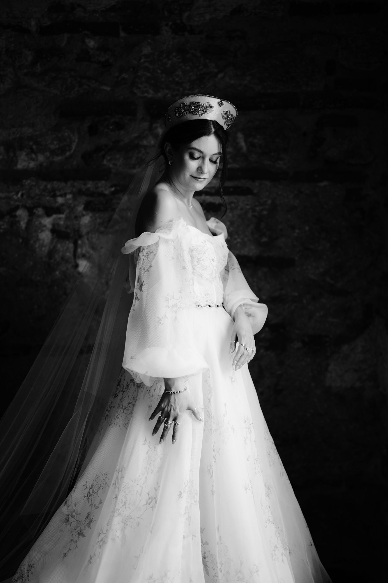 Dramatic black and white bridal portrait showcasing an off-shoulder wedding gown in a historic setting.