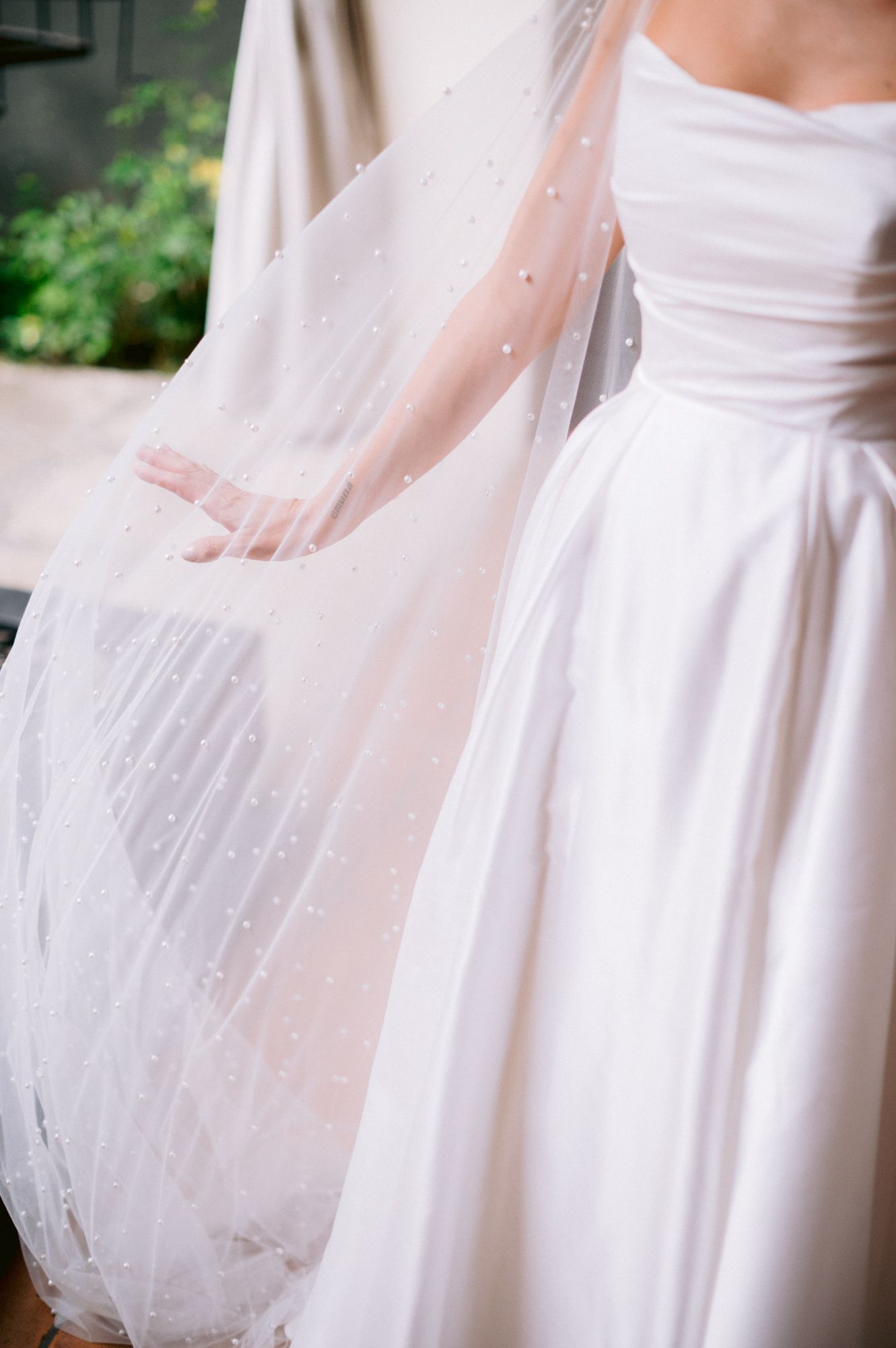 Close-up detail of a white wedding dress with delicate pearl-studded veil.
