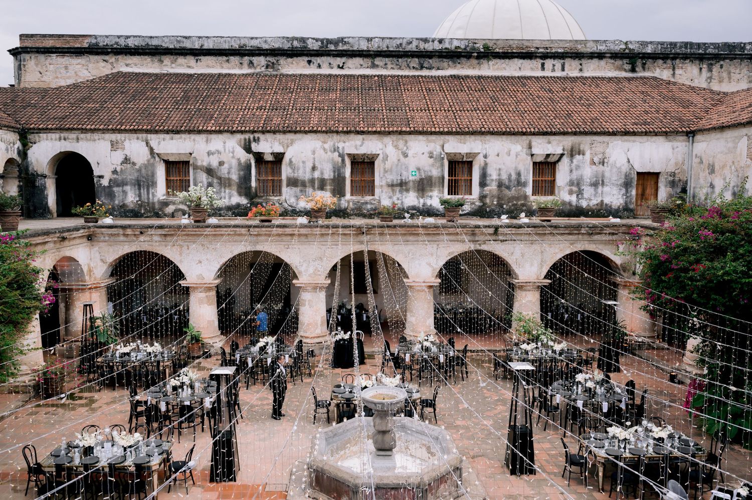 Historic courtyard venue set up for elegant wedding reception with fountain and archways.