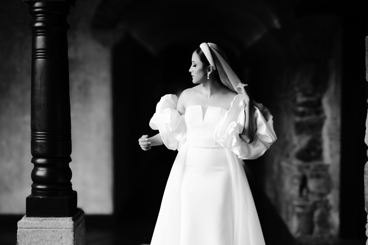 Black and white portrait of bride in off-shoulder wedding gown with dramatic puff sleeves.