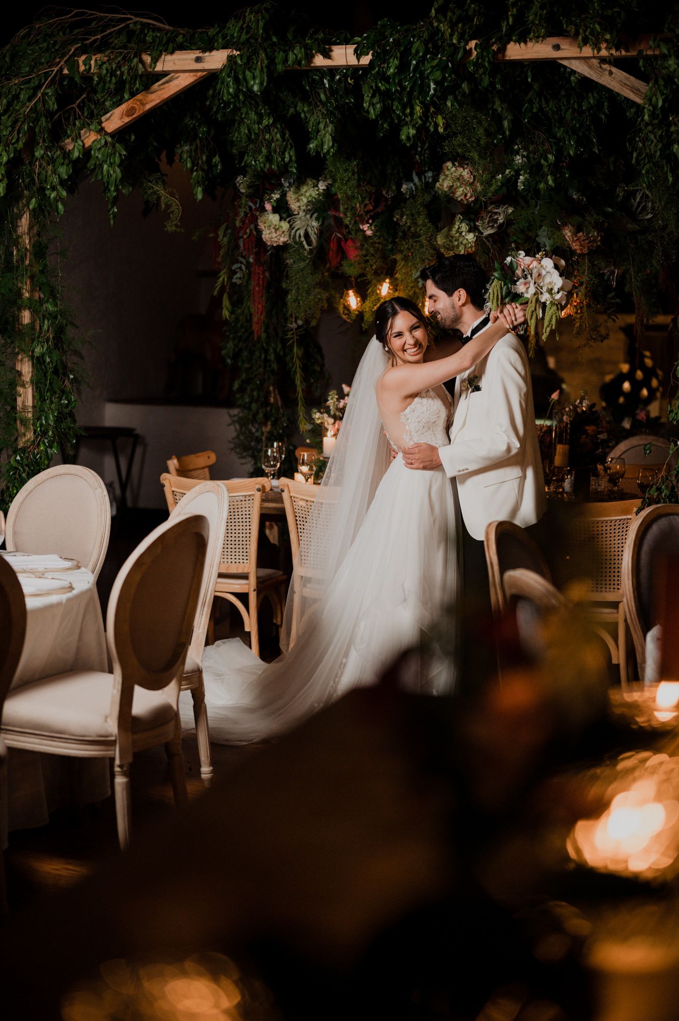 Romantic reception scene with greenery archway and candlelit ambiance.
