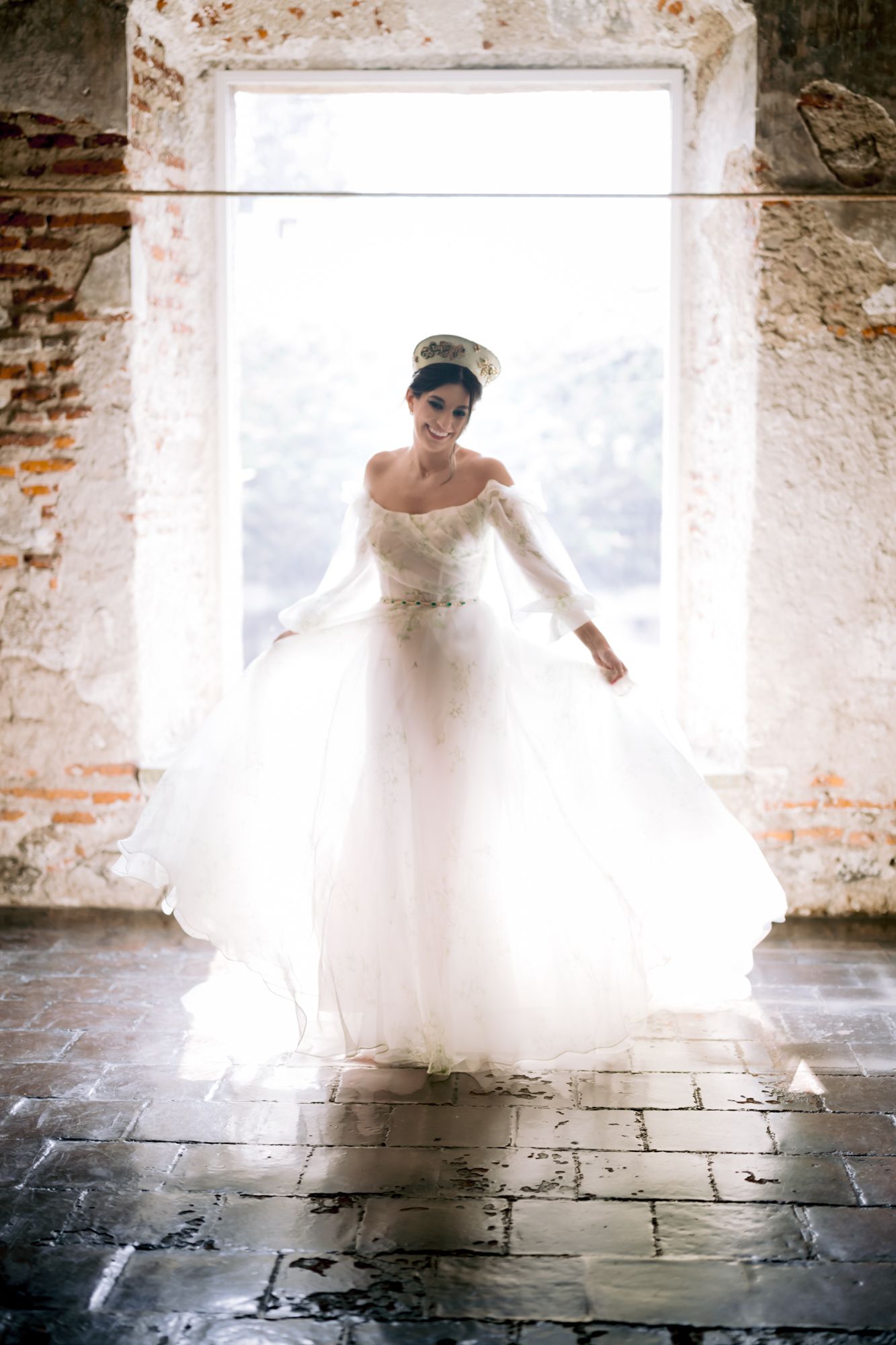 A dreamy bridal portrait in a vintage doorway shows an ethereal white wedding gown against bright backlighting.