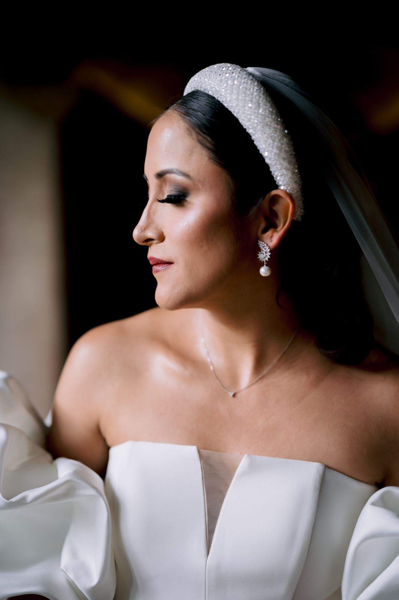 Close-up bridal portrait featuring pearl headband and drop earrings.