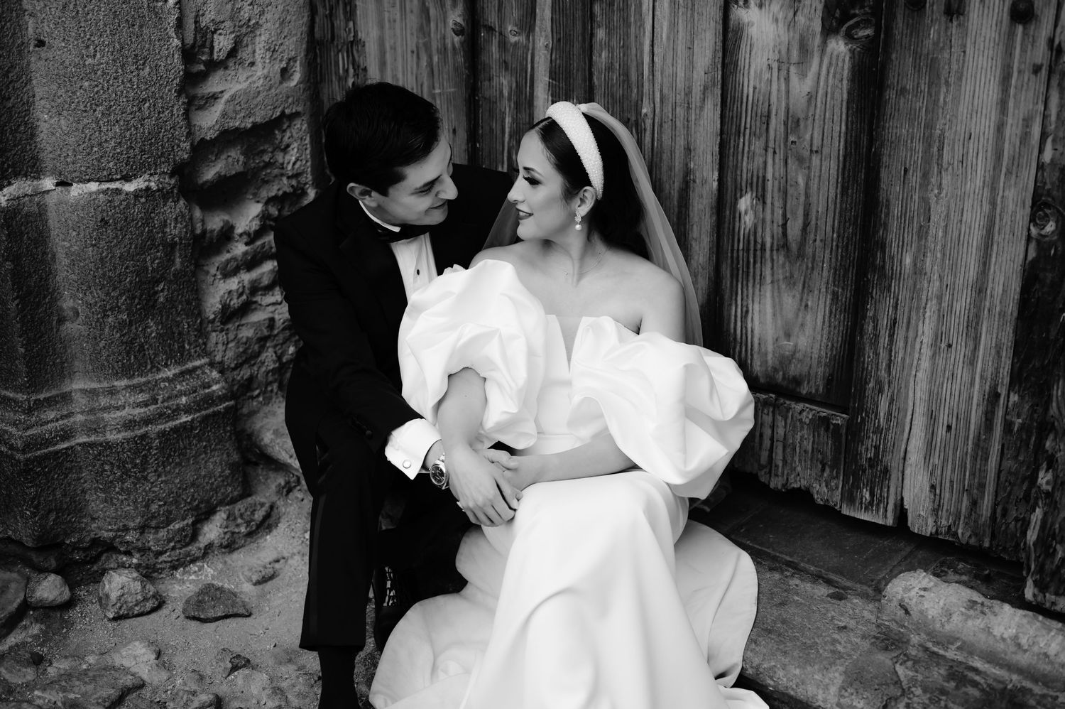Intimate black and white portrait of wedding couple embracing by vintage wooden door.