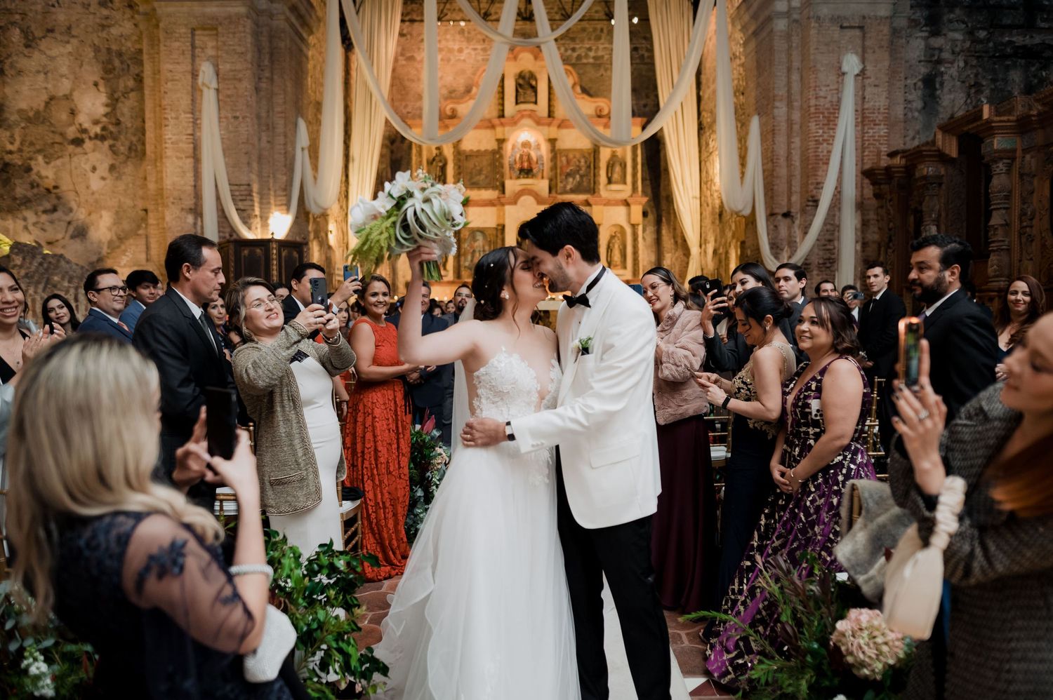Joyful wedding ceremony exit with guests looking on in beautifully decorated church.