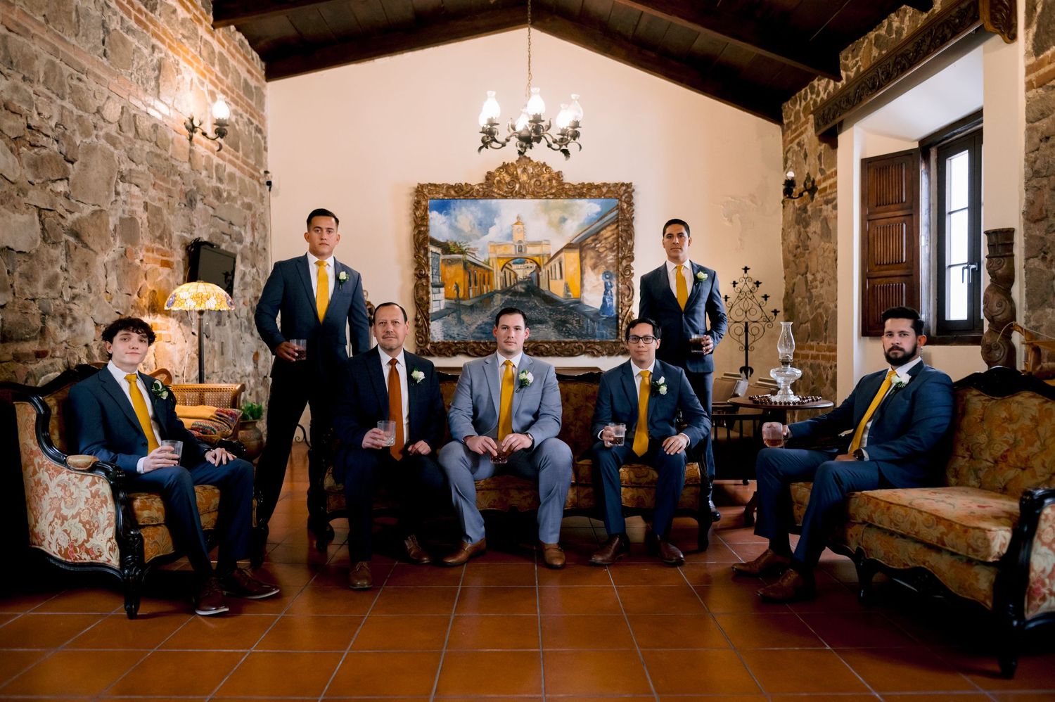 Formal group portrait in an elegant stone-walled room with traditional decor.