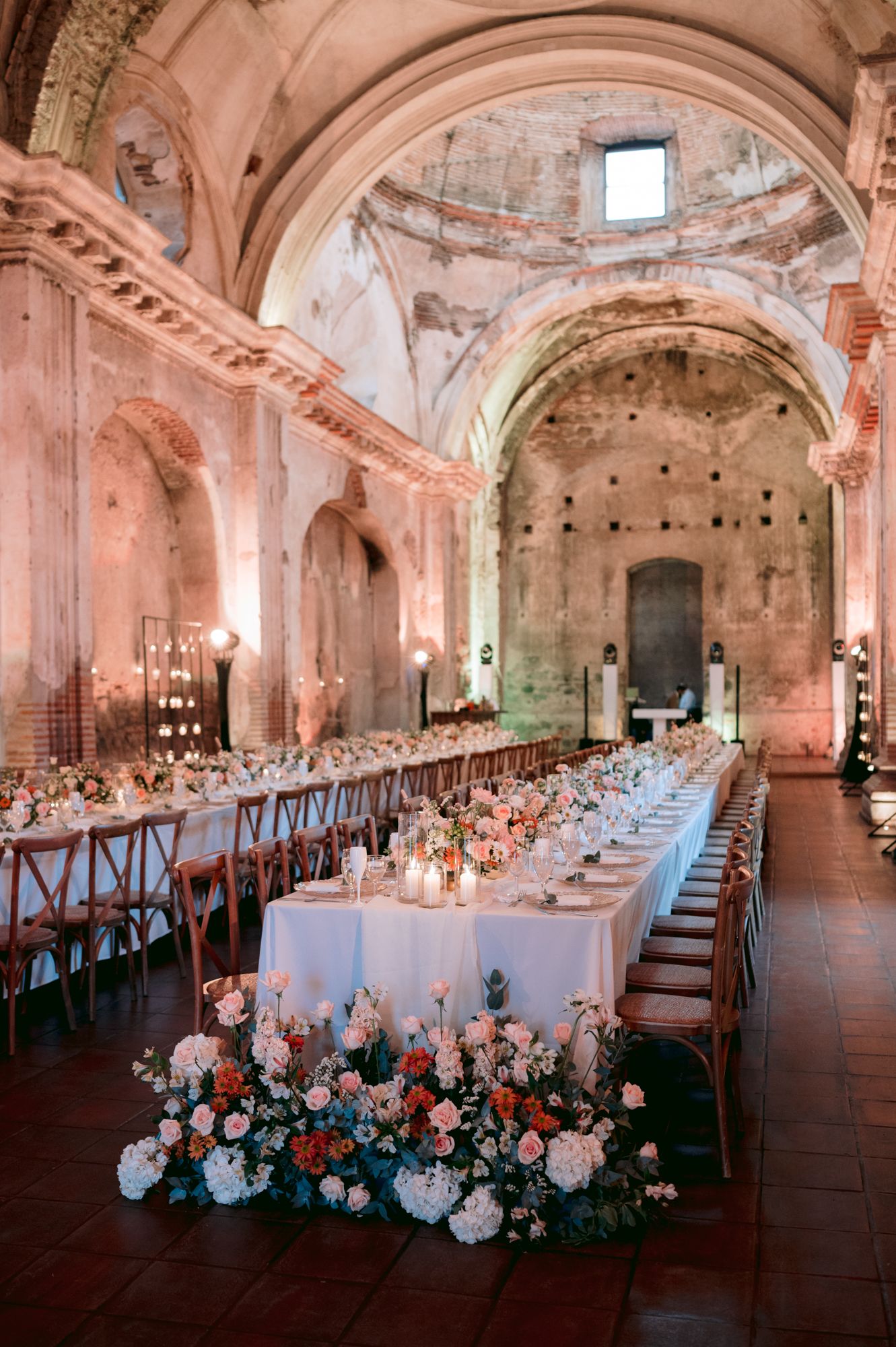 An elegant wedding reception setup with long tables and floral arrangements in a historic church setting.
