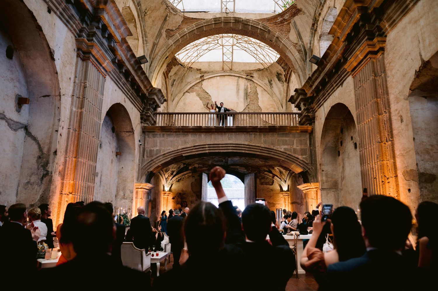 Guests observe a grand ceremony in a historic church with vaulted ceilings and ornate architecture.