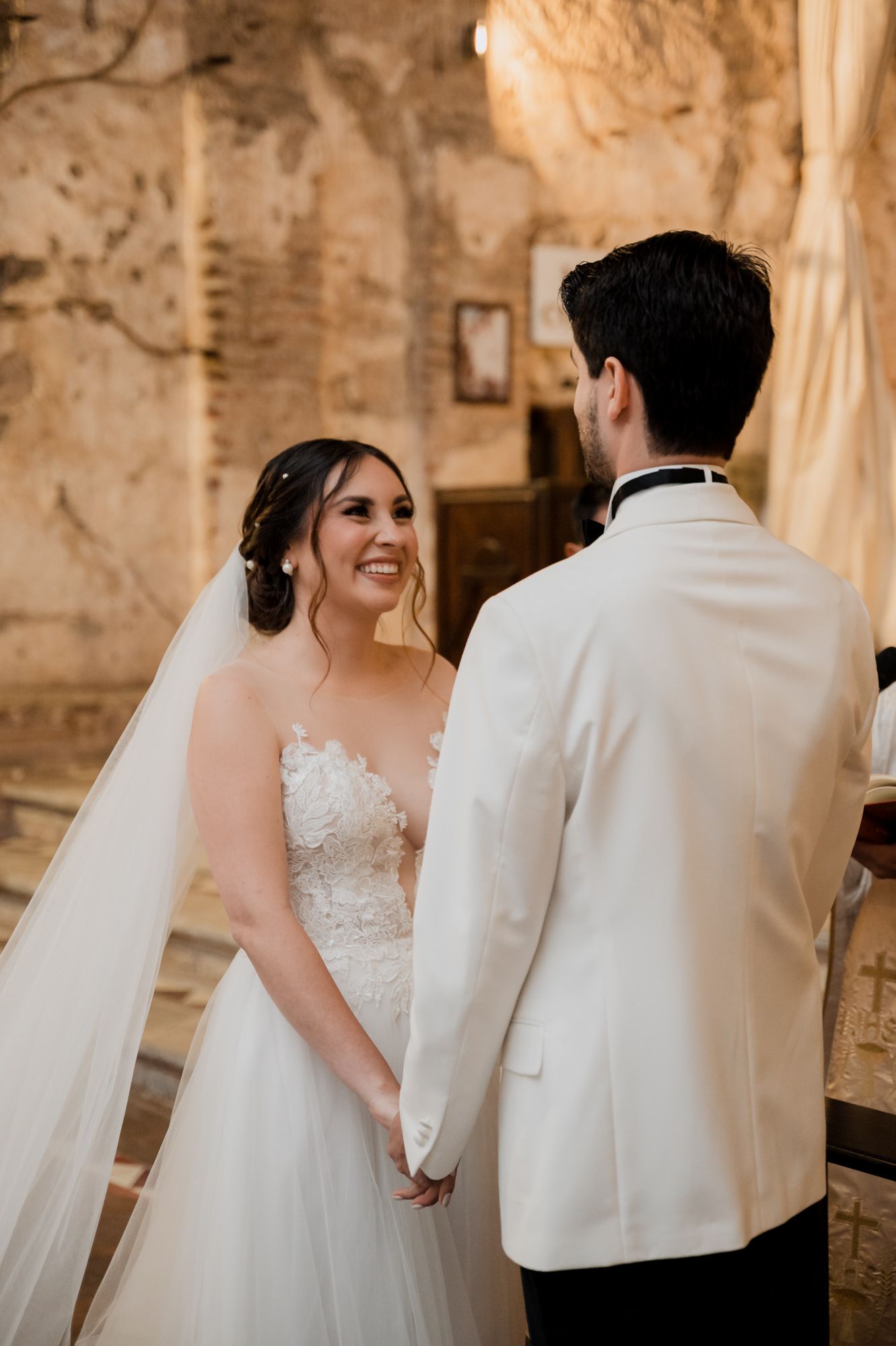A tender moment between newlyweds in a historic venue with textured stone walls.