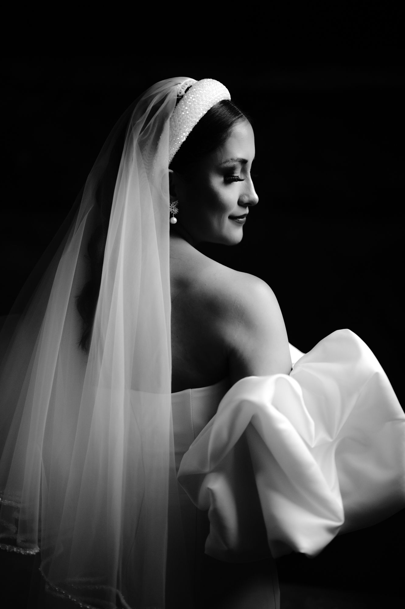 Black and white profile portrait of bride in off-shoulder wedding gown and veil.