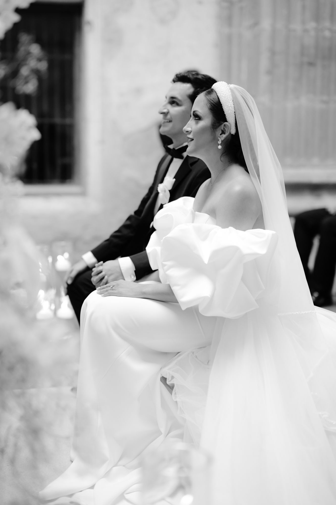 Black and white side profile of couple seated during wedding ceremony.