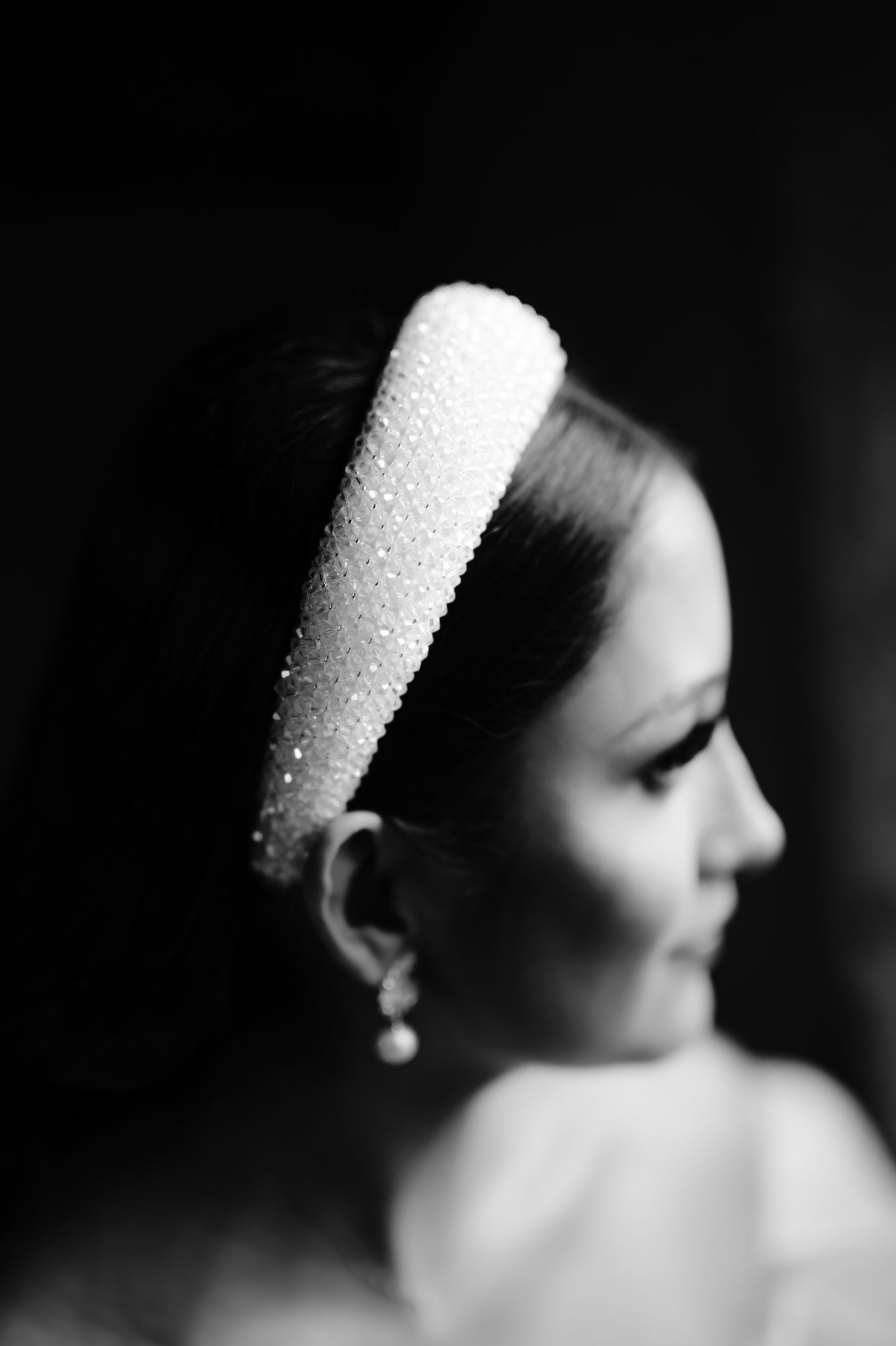 Profile view of pearl-embellished bridal headpiece and delicate earring in black and white.