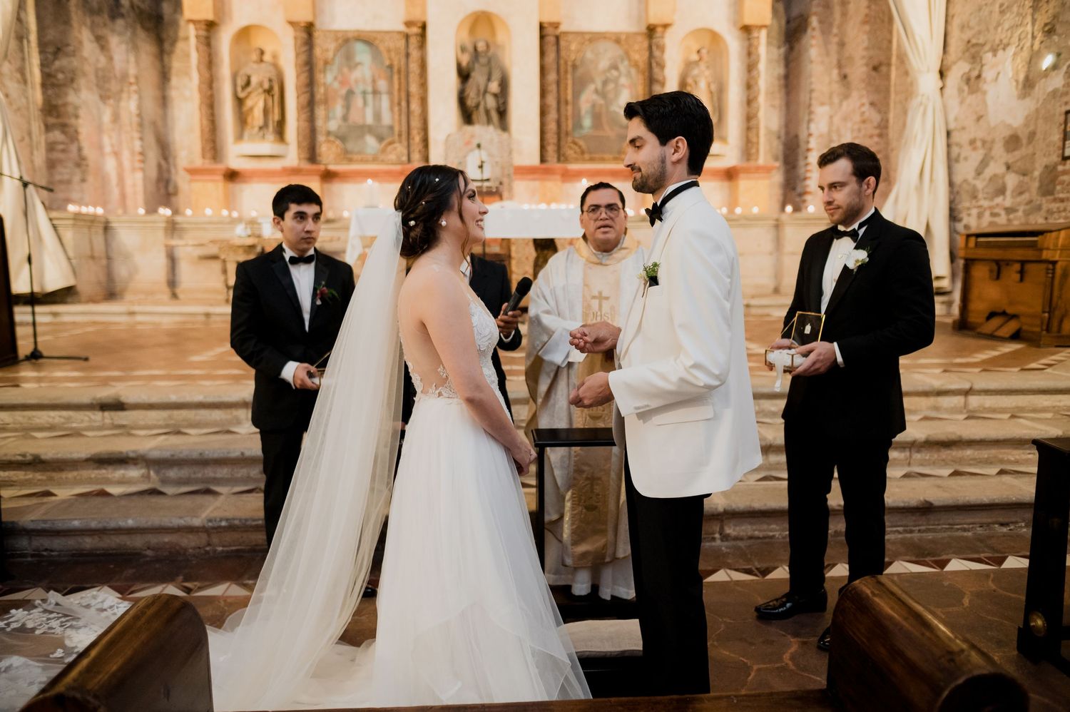 Wedding ceremony taking place in a beautiful historic church with ornate religious artwork and statues.