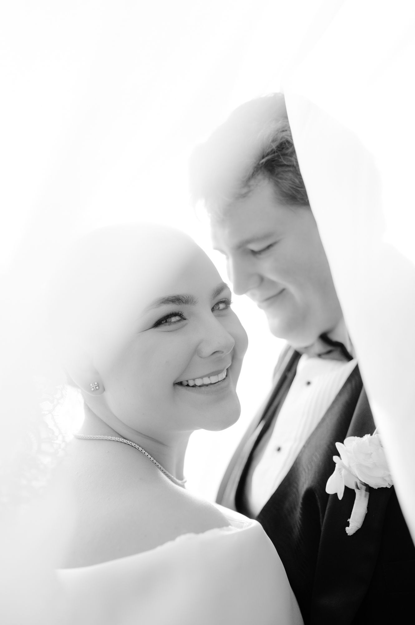 Black and white close-up portrait of a bride and groom sharing an intimate moment under her veil.