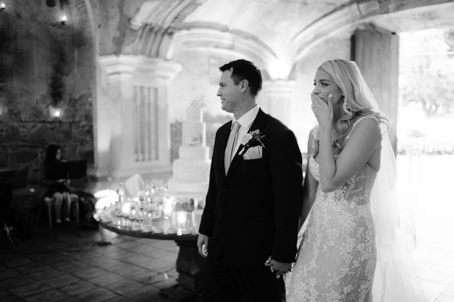 Candid black and white moment during wedding celebration in historic venue.