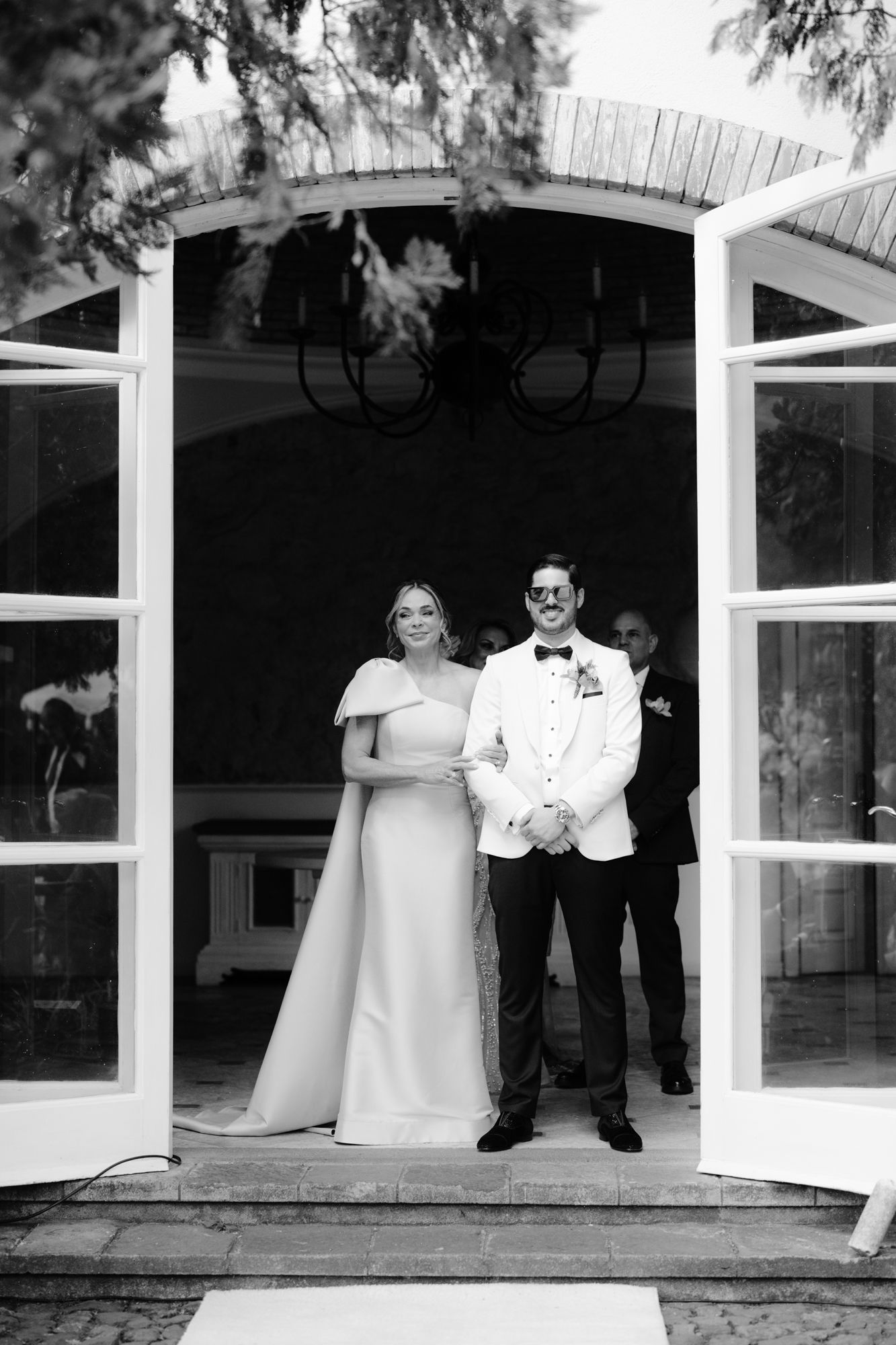 A couple stands in a white doorway archway during their formal wedding ceremony.