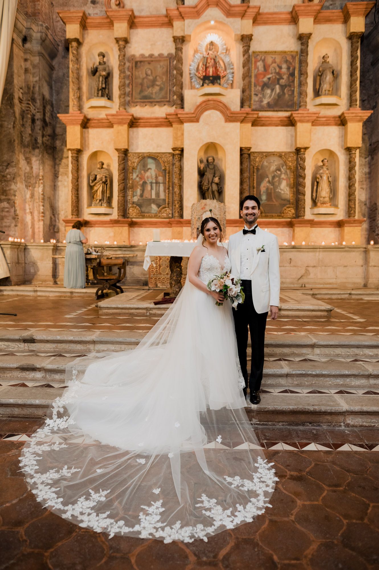 Beautiful wedding portrait in front of ornate church altar with dramatic cathedral veil.