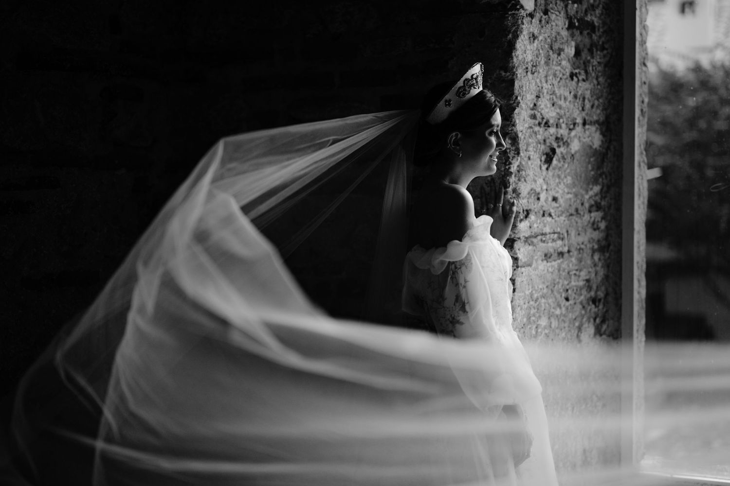 Flowing white wedding veil caught in dramatic movement against a dark background.