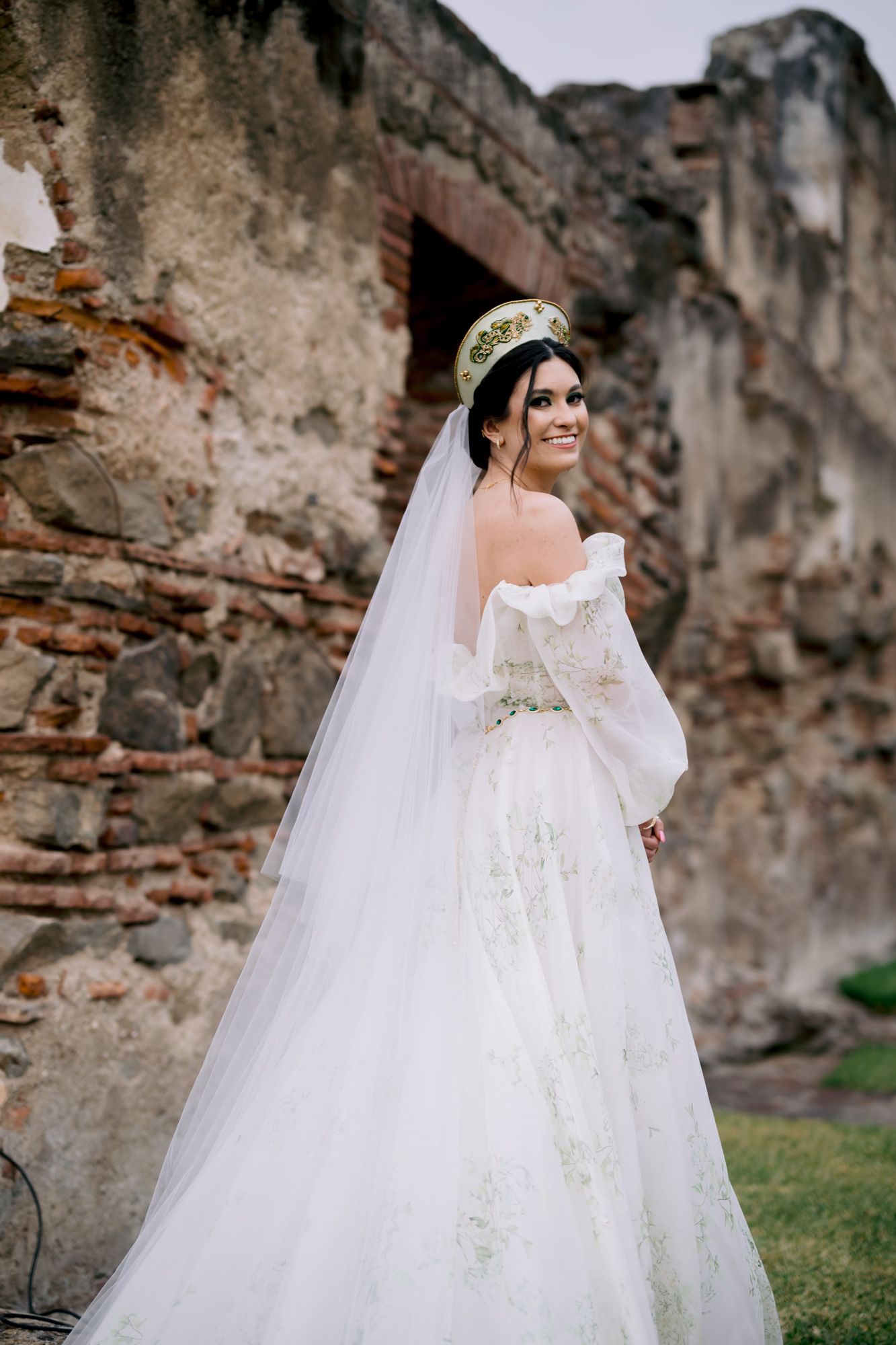 Stunning bridal portrait showcasing detailed lace gown and cathedral veil against historic ruins.